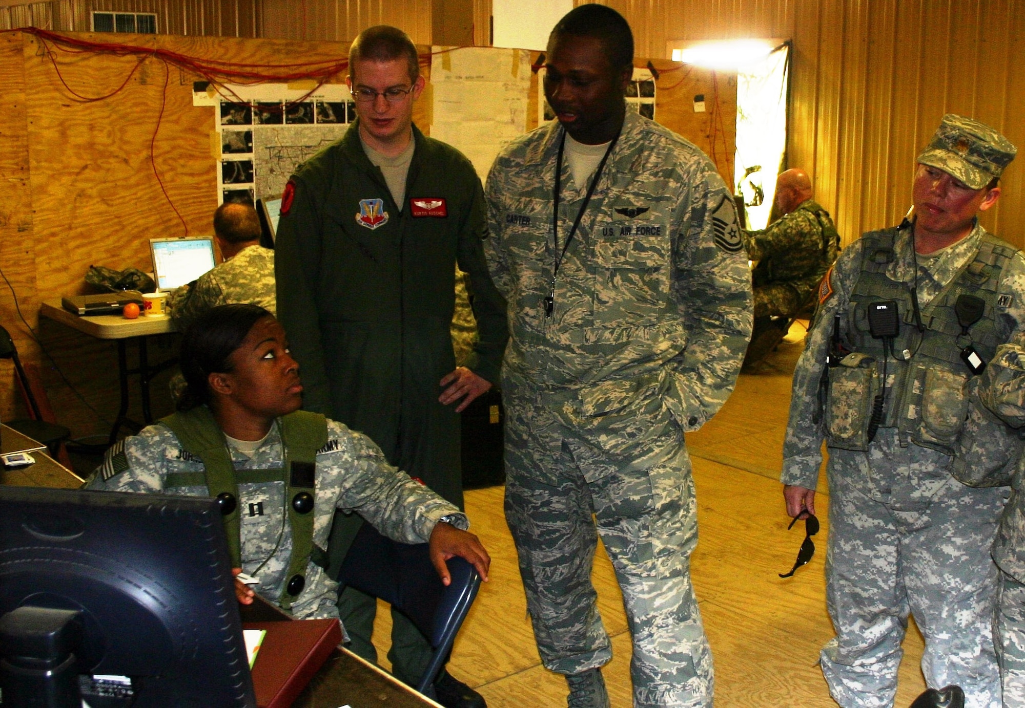 Army Capt. Lacey Johnson, collection manger, 1st BCT, 82nd (left); Air Force 1st Lt. Kurtis Kuschel, JSTARS liaison officer; Air Force Master Sgt. Ronnie Carter, JFIIT JSTARS subject matter expert; and Army Maj. Typhanie Montemayor, senior military intelligence company training mentor, JRTC discuss the BCT’s collection plan during JRTC rotation 09-06.  (Photo: Casey Bain, JFIIT, USJFCOM)