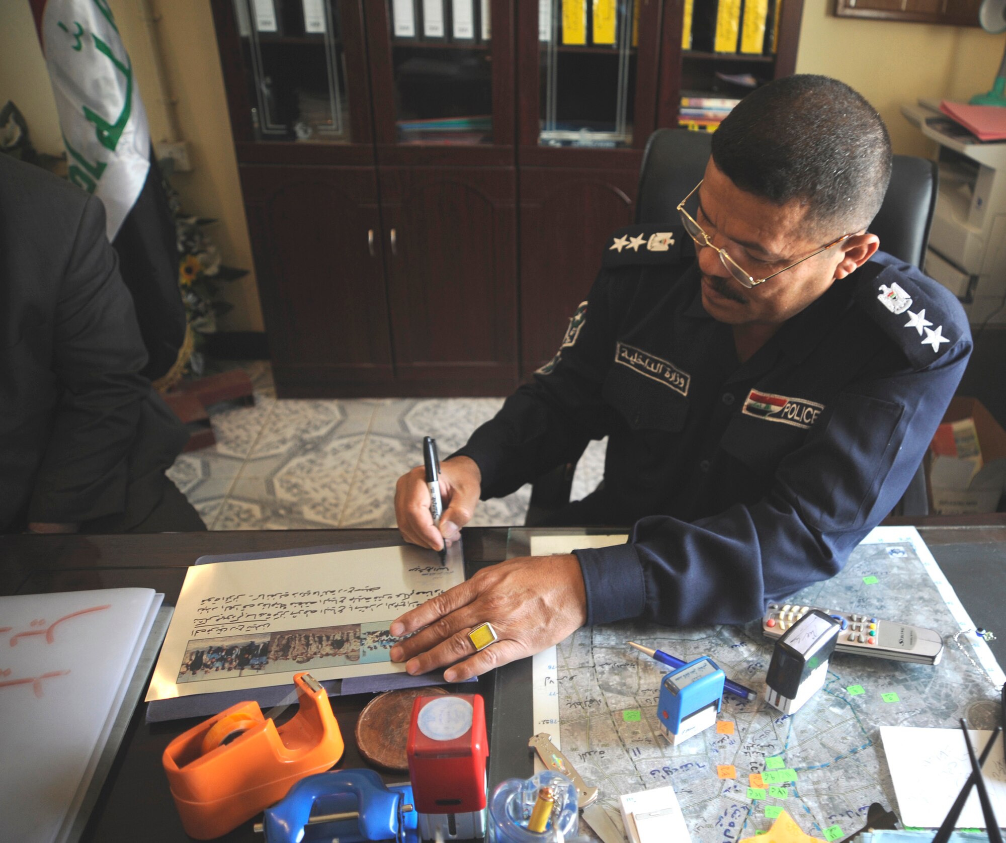 The Al Baya District Iraqi police station commander signs a plaque which will serve as a memorial for Staff Sgt. John T. Self who was killed in action two years ago when an improvised explosive device struck his vehicle May 14 in Iraq. (U.S. Air Force photo/Staff Sgt. Shawn Weismiller) 
