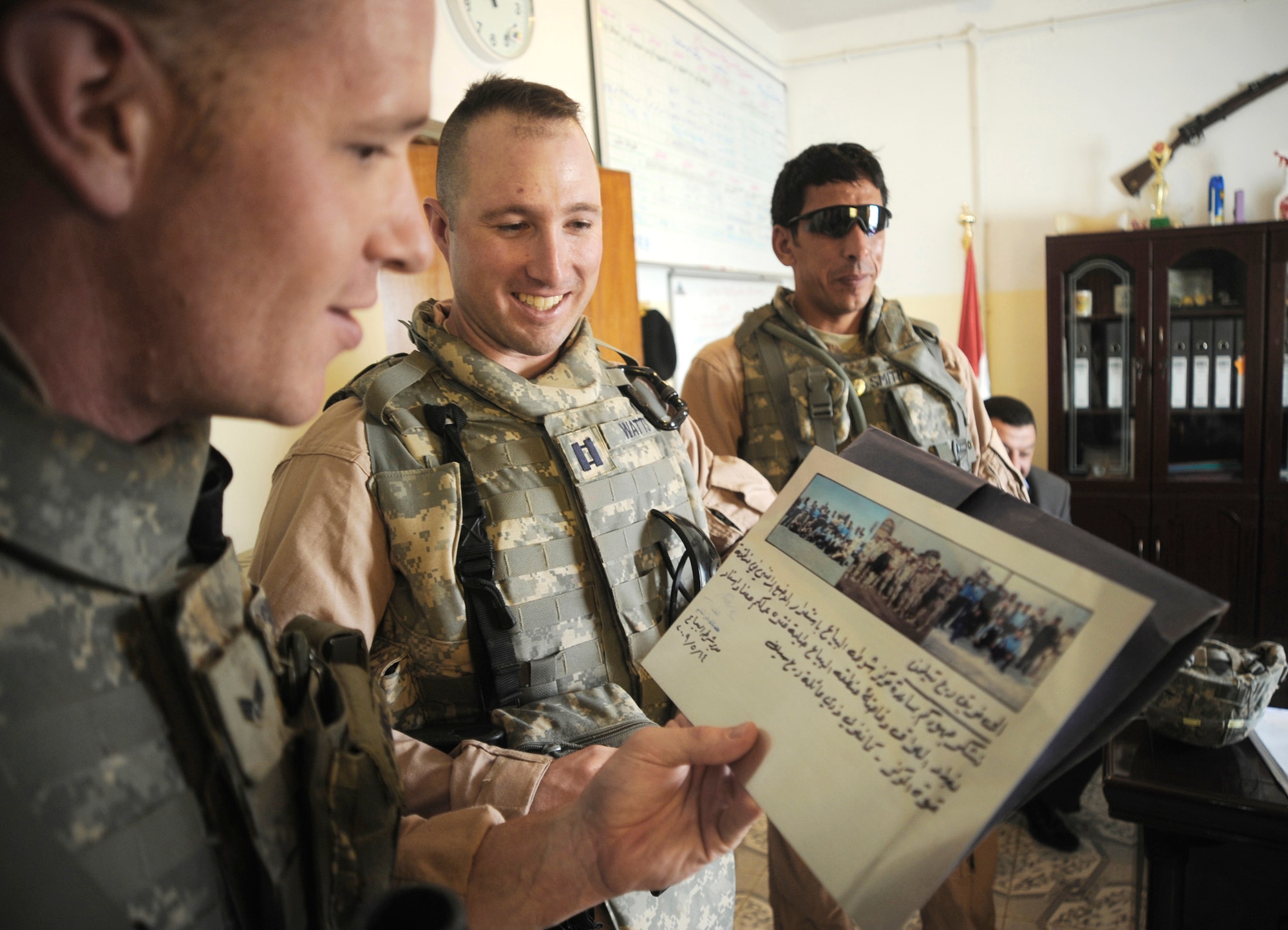 Capt. David Watts and Senior Airman Cole Magin reminisce as they look at pictures on a plaque used as a memorial for Staff Sgt. John T. Self who was killed in action two years ago when an improvised explosive device struck his vehicle May 14 in Iraq. Captain Watts and Airman Magin served with Sergeant Self and currently are deployed in support of Operation Iraqi Freedom. (U.S. Air Force photo/Staff Sgt. Shawn Weismiller) 
