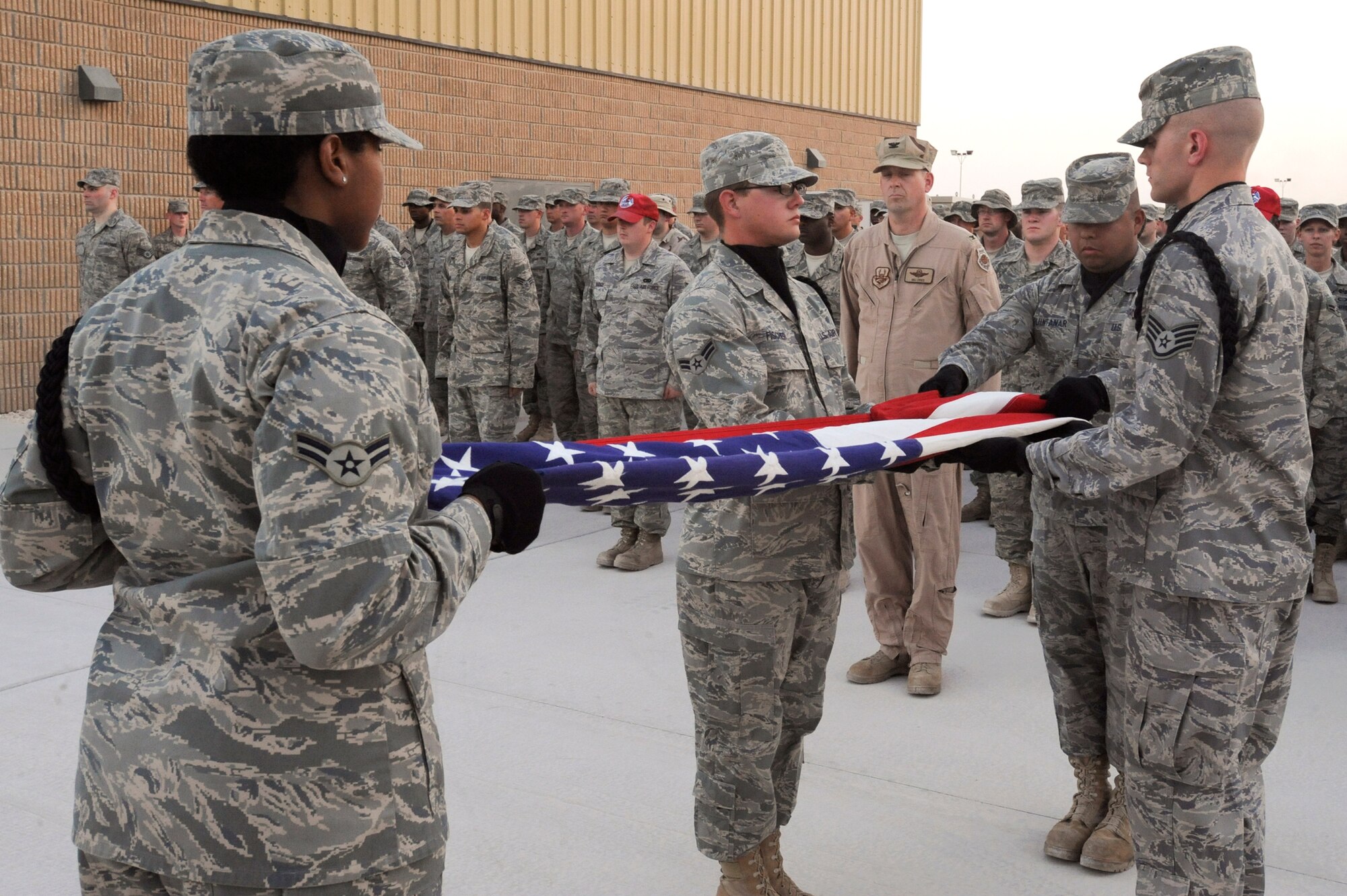 Members of the 379th Air Expeditionary Wing Honor Guard Team, fold the United States flag in front of a wing formation during a Memorial Day retreat ceremony here, May 25, 2009, in an undisclosed location in Southwest Asia.  The retreat was held to remember and honor all those who have died in service to the United States.  All members are deployed in support of Operations Iraqi and Enduring Freedom and Combined Joint Task Force - Horn of Africa.  (U.S. Air Force Photo by Staff Sgt. Joshua Garcia/released)