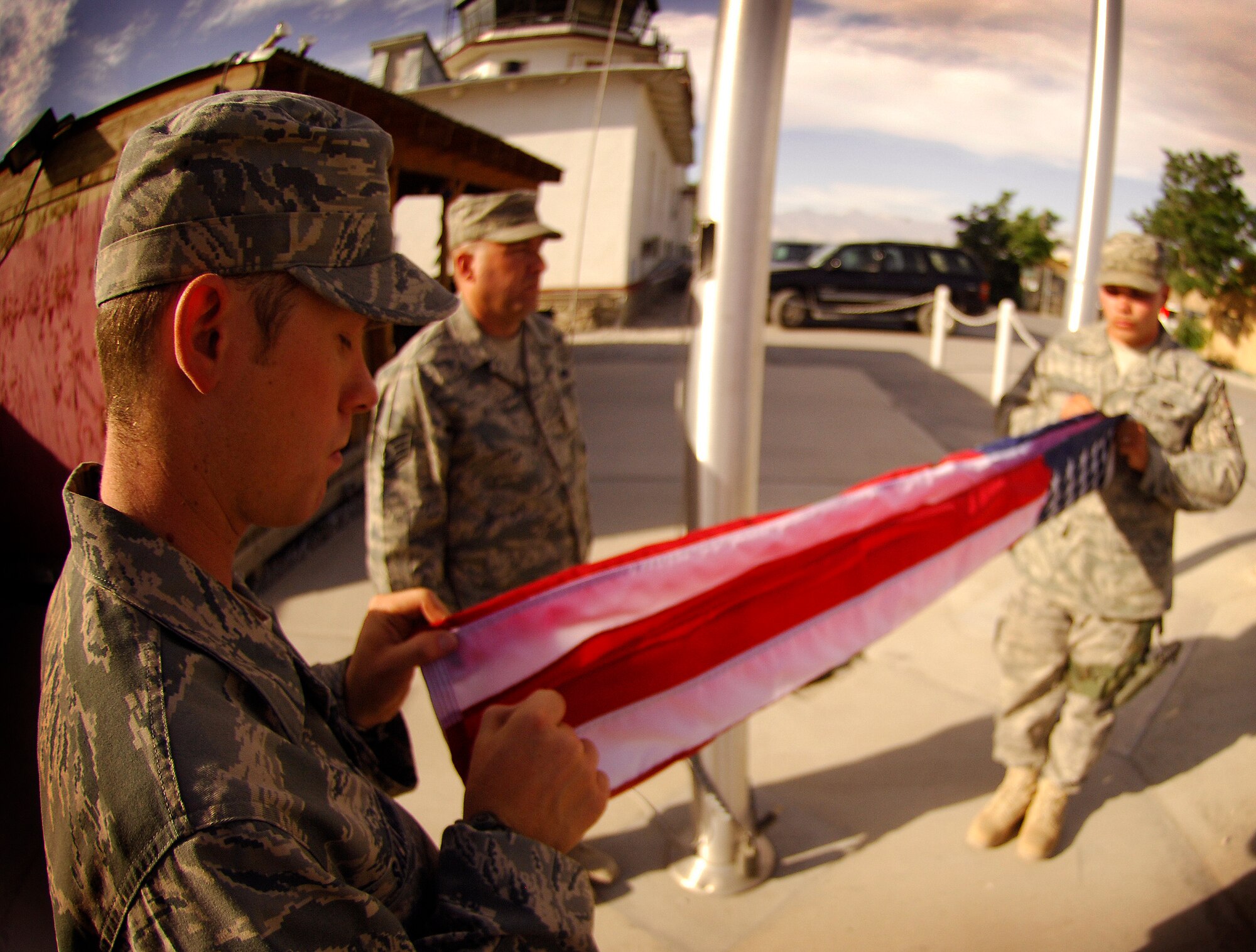 Staff Sgts. Scott Salamone and Christopher Naylor and Senior Airman Sheldon Hanson-Molina from the 455th Expeditionary Civil Engineer Squadron force protection, participate in a Memorial Day ceremony here at Camp Cunningham May 25. A team of seven Air Force honor guardsmen flew and folded nearly 50 flags over a three-hour period on behalf of the 455th Air Expeditionary Wing. The flags and a certificate will be sent home to friends and family of servicemembers in honor of the national holiday. (Air Force/Staff Sgt. Jason Lake) 