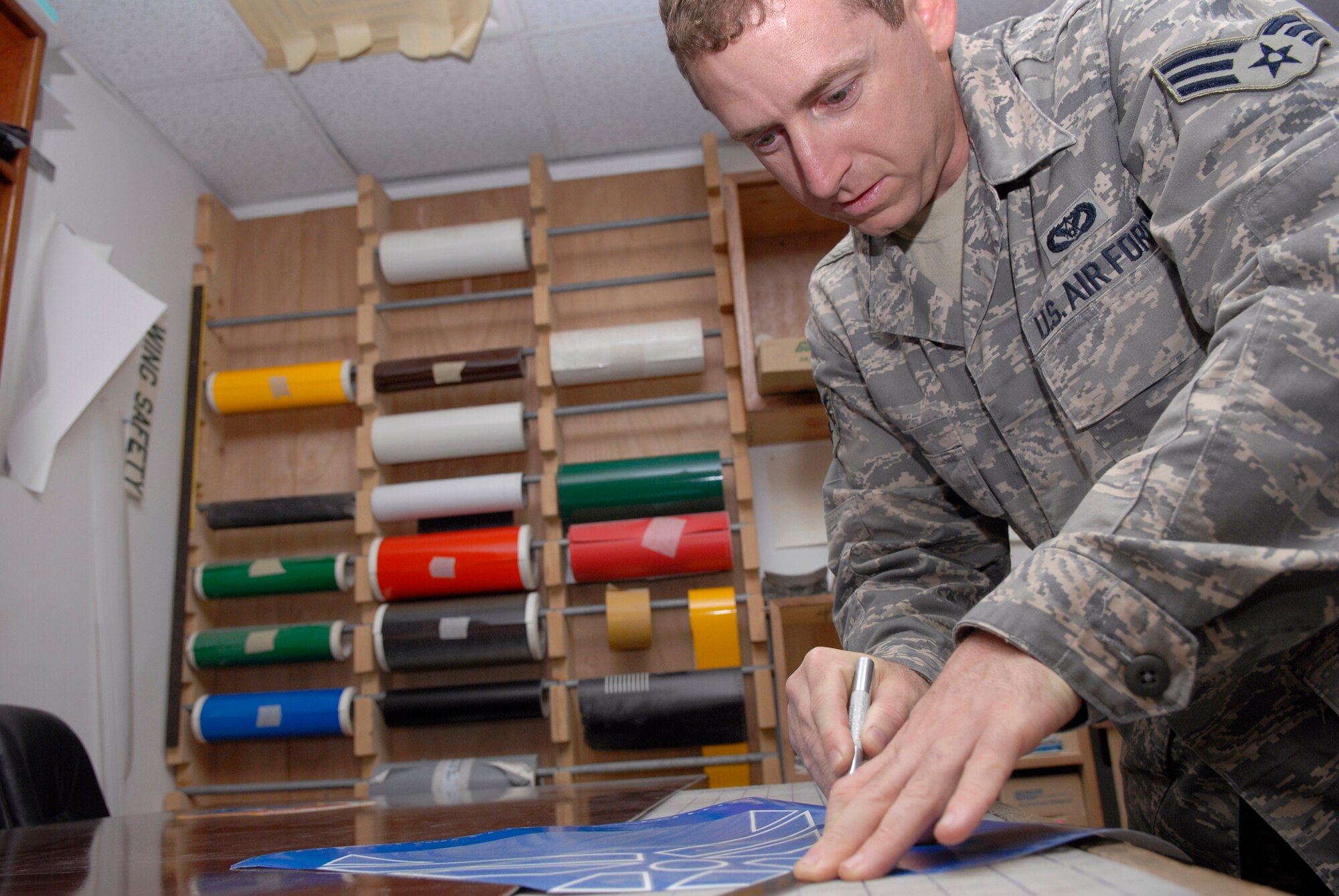 Senior Airman Geoffrey Witte, 379th Expeditionary Civil Engineer Structural Journeyman, cuts out the Air Force symbol from vinyl for a new Wing Operations Center sign, May 21, 2009, at an undisclosed location in Southwest Asia.  The sign shop uses an array of materials to create building, road, and other signs used throughout the base.  Airman Witte hails from Anadarko, Okla. and is deployed from Vandenberg Air Force Base, Calif. in support of Operations Iraqi and Enduring Freedom and Combined Joint Task Force - Horn of Africa.  (U.S. Air Force photo/Senior Airman Andrew Satran/released) 