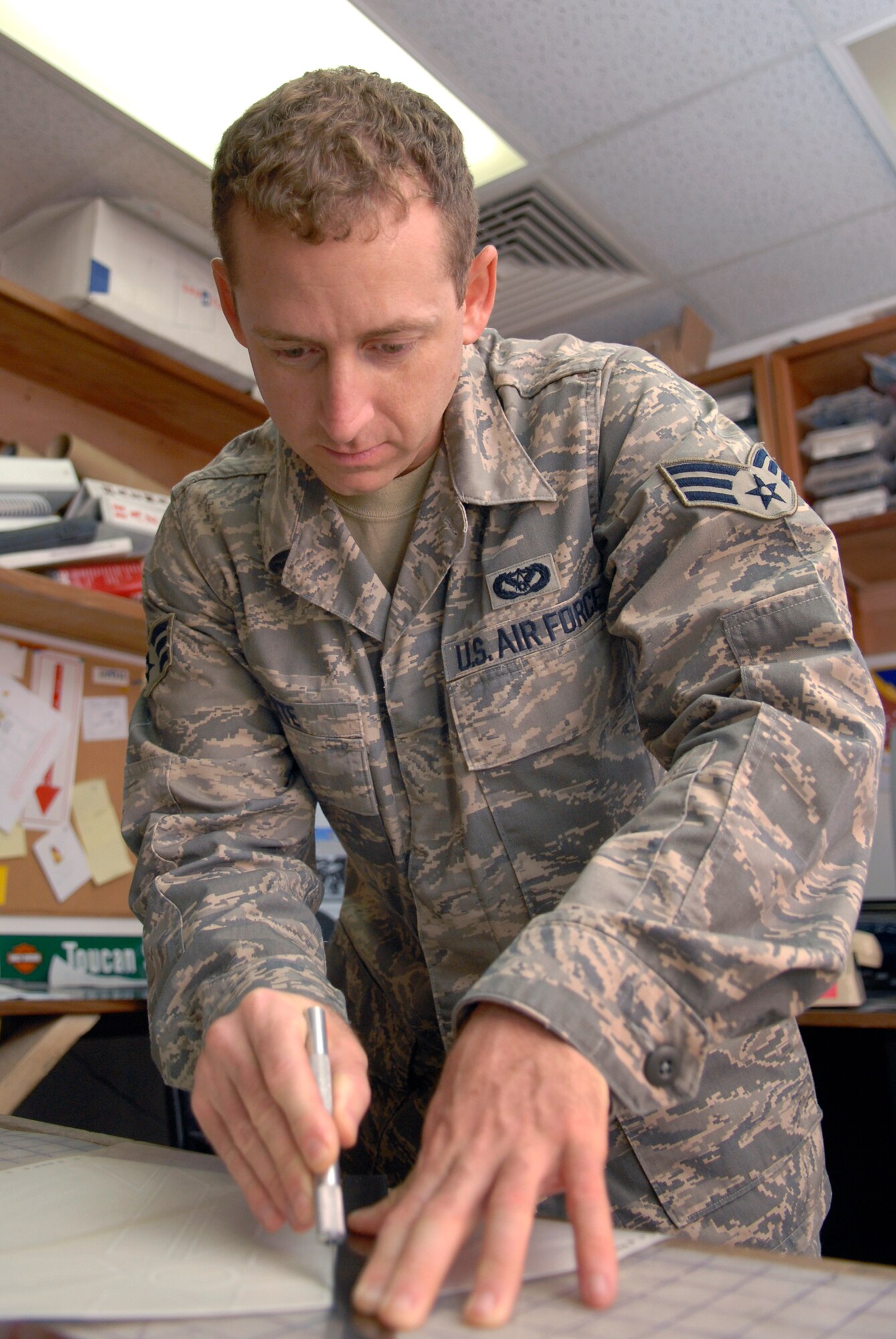 Senior Airman Geoffrey Witte, 379th Expeditionary Civil Engineer Structural Journeyman, cuts out a template of the Air Force symbol which he will use to cut the symbol from vinyl for a new Wing Operations Center sign, May 21, 2009, at an undisclosed location in Southwest Asia.  The sign shop uses an array of materials to create building, road, and other signs used throughout the base.  Airman Witte hails from Anadarko, Okla. and is deployed from Vandenberg Air Force Base, Calif. in support of Operations Iraqi and Enduring Freedom and Combined Joint Task Force - Horn of Africa.  (U.S. Air Force photo/Senior Airman Andrew Satran/released) 