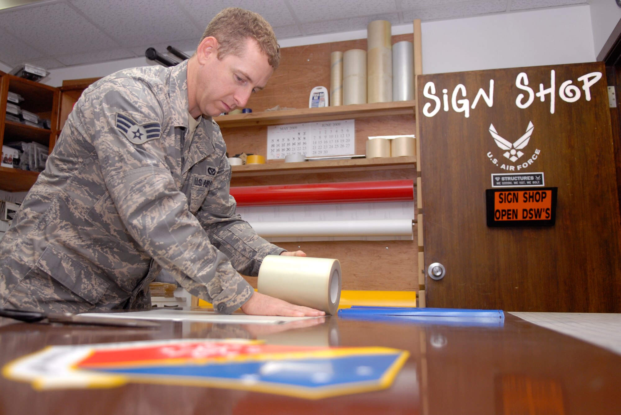 Senior Airman Geoffrey Witte, a 379th Expeditionary Civil Engineer structural journeyman, works to place vinyl emblems on a piece of sheet metal for a new Wing Operations Center sign, May 21, 2009, at an undisclosed location in Southwest Asia.  The sign shop uses an array of materials to create building, road, and other signs used throughout the base.  Airman Witte hails from Anadarko, Okla. and is deployed from Vandenberg Air Force Base, Calif. in support of Operations Iraqi and Enduring Freedom and Combined Joint Task Force - Horn of Africa.  (U.S. Air Force photo/Senior Airman Andrew Satran/released)