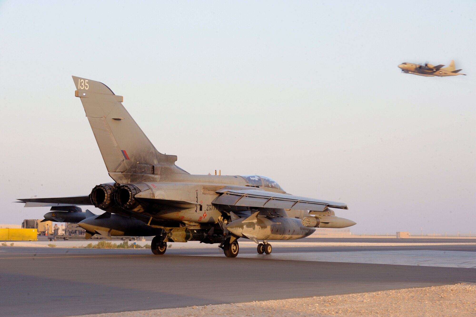 A Royal Air Force Tornado with the 2nd Squadron Tornado Detachment taxi's to the runway for an early morning mission as a U.S. Navy P-3 Orion takes off in the background, May 25, 2009, in an undisclosed location in Southwest Asia.  The Tornado Detachment will cease operations from this location in the coming weeks. (U.S. Air Force Photo by Staff Sgt. Joshua Garcia/released)