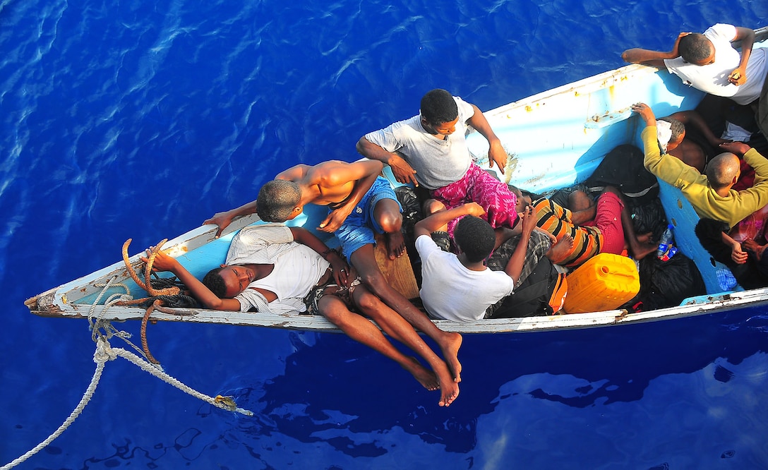 Somali migrants in a disabled skiff wait for assistance from U.S. Navy sailors assigned to the guided-missile cruiser USS Lake Champlain  in the Gulf of Aden, May 24, 2009. Children aboard the disabled skiff were transported to the USS Lake Champlain separately.