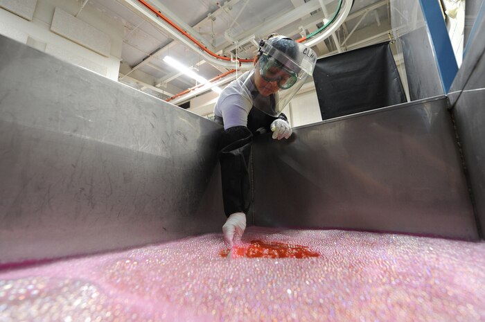U.S. Air Force Senior Airman Lilia Linares dips a piece of metal into a tank of  emulsifier to remove excess liquid dye penetrate at Charleston Air Force Base S.C., May 27, 2009. The non-destructive inspection section inspects more than 40,000 pieces of weapon systems and non-weapon systems assets a year. Airman Linares is a non-destructive journeyman with the 437th Maintenance Squadron. (U.S. Air Force photo by James M. Bowman)(Released)