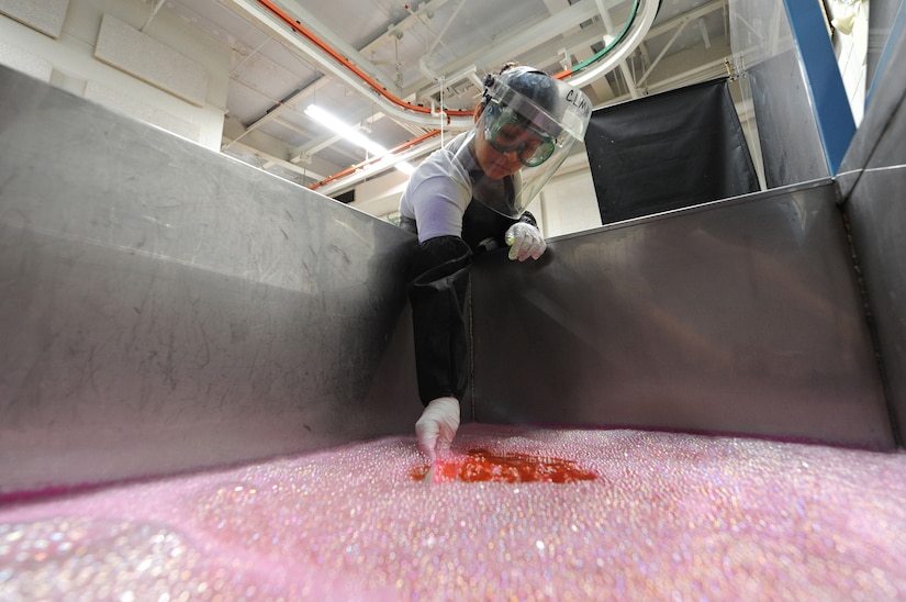 U.S. Air Force Senior Airman Lilia Linares dips a piece of metal into a tank of  emulsifier to remove excess liquid dye penetrate at Charleston Air Force Base S.C., May 27, 2009. The non-destructive inspection section inspects more than 40,000 pieces of weapon systems and non-weapon systems assets a year. Airman Linares is a non-destructive journeyman with the 437th Maintenance Squadron. (U.S. Air Force photo by James M. Bowman)(Released)
