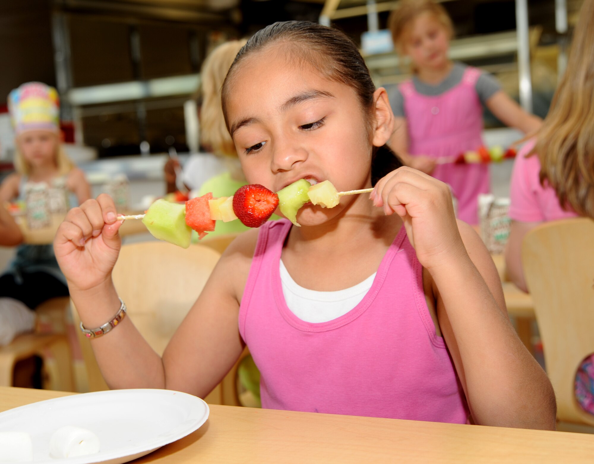 MCCONNELL AIR FORCE BASE, Kan. -- Selina Mejia, 8, daughter of Senior Airman Anthony Mejia, 22nd Air Refueling Wing, eats a fruit ka-bob at the School Age Program, May 21. The program provides a place for active-duty school aged family members to keep busy during schools holidays and after school hours. (Photo by Senior Airman Roy Lynch) 