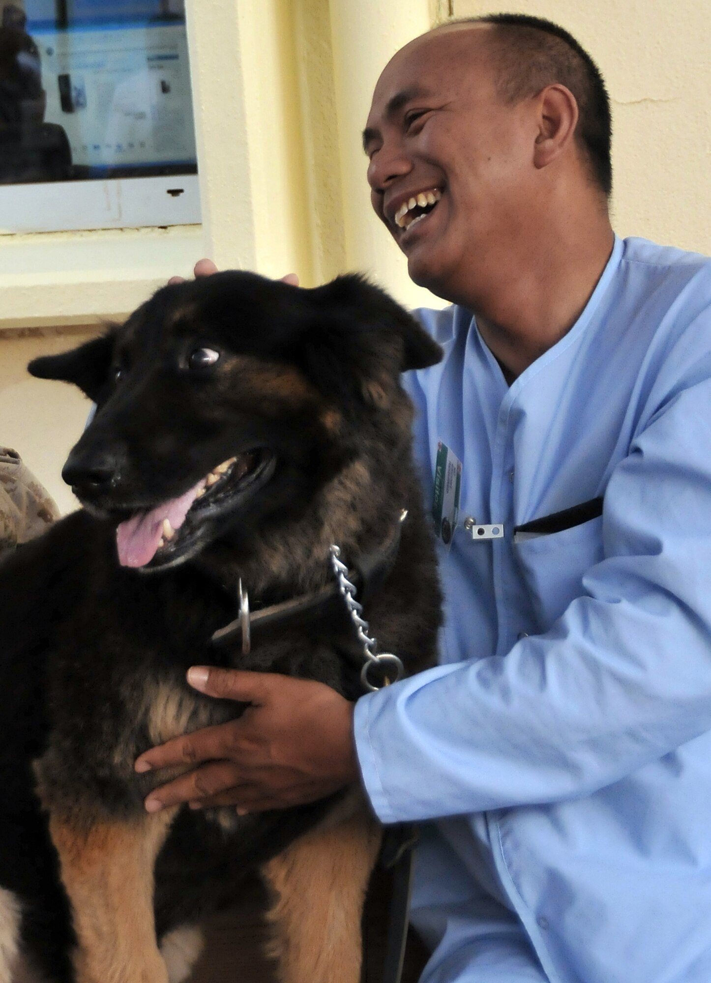Army Spc. Than Kywe shares a laugh with Cezar, a 332nd Expeditionary Security Forces Group explosives-detection military working dog, during the first session of the K-9 Visitation Program May 15 at Joint Base Balad, Iraq. Specialist Kywe is an Air Force Theater Hospital patient. The program works to further patient recovery after injury or illness through animal-assisted therapy. (U.S. Air Force photo/Staff Sgt. Dilia Ayala) 

