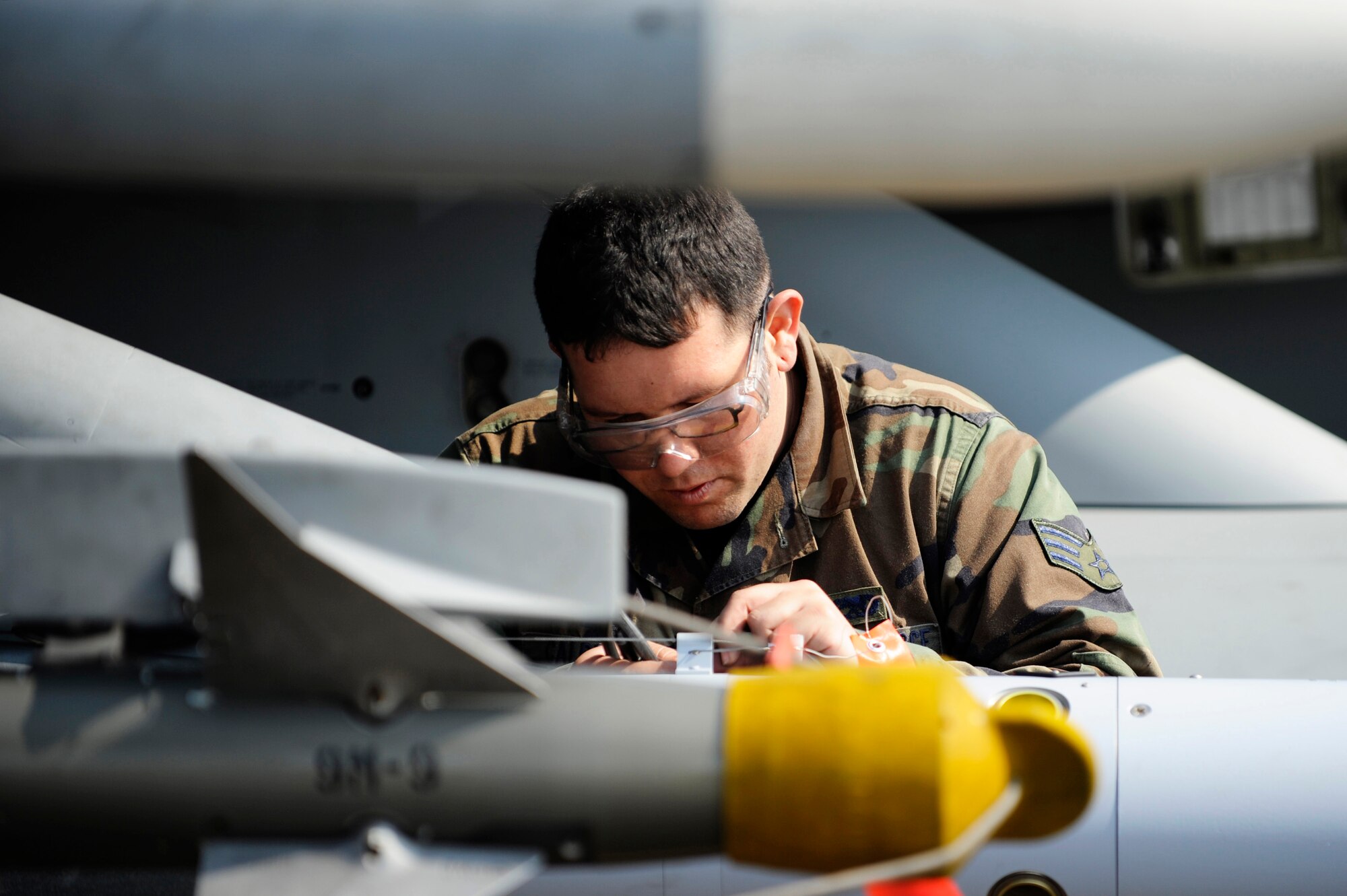Senior Airman Gilbert Calderon arms a live guided bomb unit-12 on an F-16 Fighting Falcon during Distant Frontier exercise May 08, 2009, Eielson Air Force Base, Alaska. This exercise provides 35th Aircraft Maintenance Unit weapons load crew practice loading a variety of live munitions and pilots will utilize the Joint Pacific Alaskan Range Complex by dropping their entire years supply in a matter of two weeks. Airman Calderon is a weapons load crew member assigned to the 35th Aircraft Maintenance Unit, Kunsan Air Base, Korea.  (U.S. Air Force Photo/Senior Airman Jonathan Snyder)