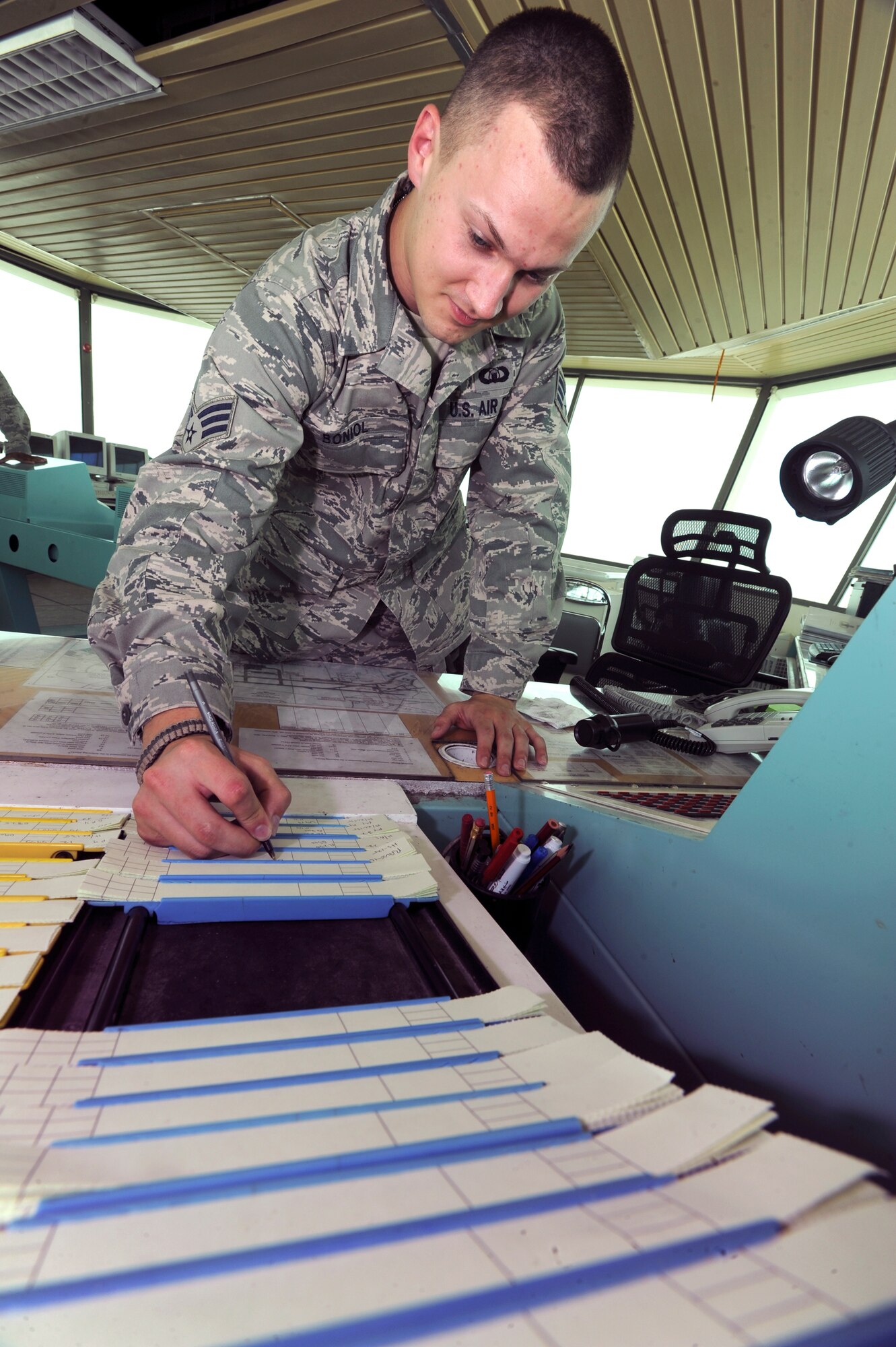 Senior Airman Stephen Boniol writes status of an aircraft on a flight progress strip May 18, 2009 at an air base in Southwest Asia. The flight progress strips hold aircraft information including departure point, destination and flight altitude. Airman Boniol is a 379th Expeditionary Operations Support Squadron air traffic controller deployed from Alexandria Air National Guard Base, La. (U.S. Air Force photo/Staff Sgt. Joshua Garcia) 
