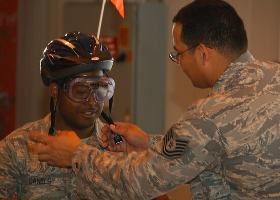 Vance AFB’s Safety Day Expo featured safety as the number one priority for the base. Master Sgt.  Edward Daniels from the Force Support Squadron is fitted with a helmet by Tech. Sgt. Jon Cabatit before attempting the tricycle obstacle course. He is wearing “beer goggles” to simulate the effects of slower reflexes and impaired vision caused by alcohol consumption. The Safety Day Expo took the place of a traditional safety briefing and was open 9 a.m. to 11 a.m, May 22, in Hangar 170 to kick-off the 101 Critical Days of Summer. (U.S. Air Force Photo/Staff Sgt. Brian Hill)