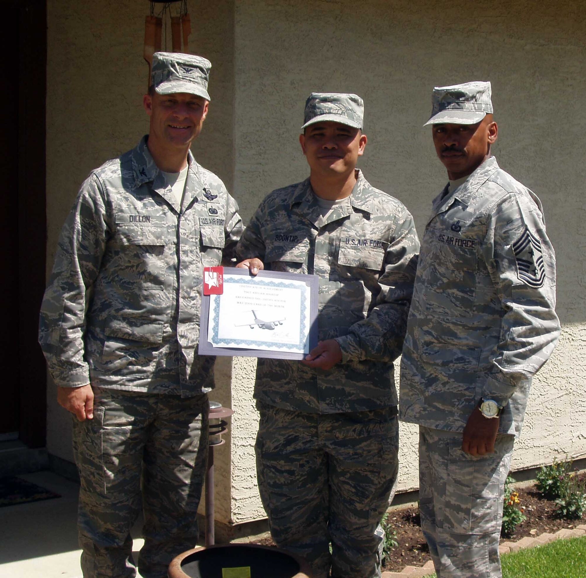 Col. Mark Dillon, 60th Air Mobility Wing commander, and Chief Master Sgt. Michael Williams, 60th AMW command chief, present the Yard of the Month Award to Tech. Sgt. Anucha Boontip, 573rd Global Support Squadron. Sergeant Boontip’s yard was recognized for pride in ownership, outstanding curb appeal and overall appearance. (U.S. Air Force photo/Master Sgt. Calvin Baumann)