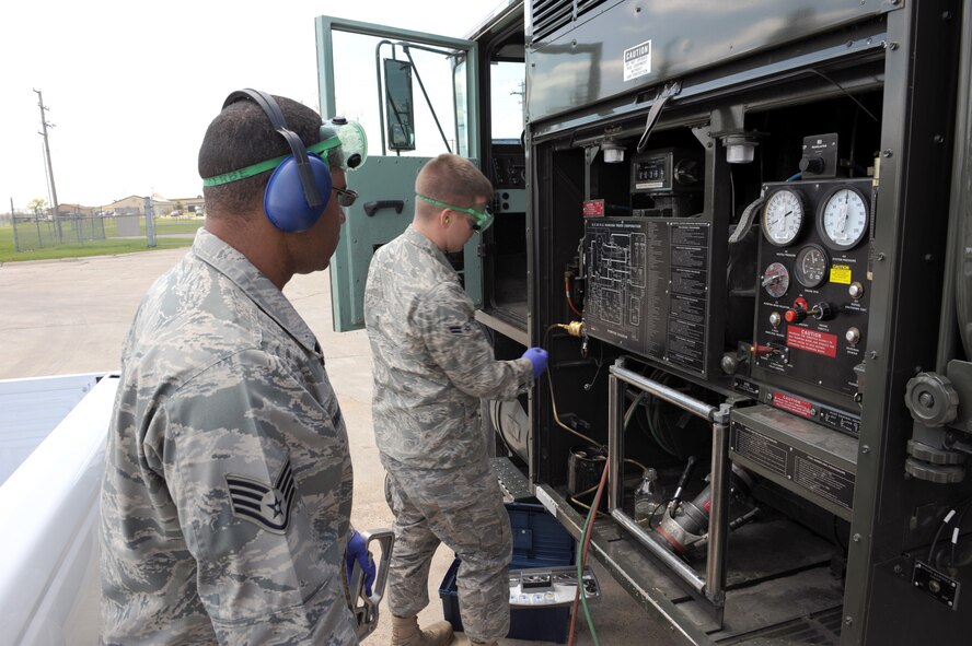 MINOT AIR FORCE BASE, ND -- Staff Sgt. Isaac Robinson, 5th Logistics Readiness Squadron fuels laboratory non commissioned officer in charge, assists Airman 1st Class John Fleming, 5th LRS fuels laboratory technician, with removing fuel from R-11 tanker trucks for conducting quality control procedures here May 26.  The fuels laboratory checks the water content, color and contamination level of the fuel weekly to ensure its safe usage in aircraft. (U.S. Air Force photo by Staff Sgt. Keith Ballard)
