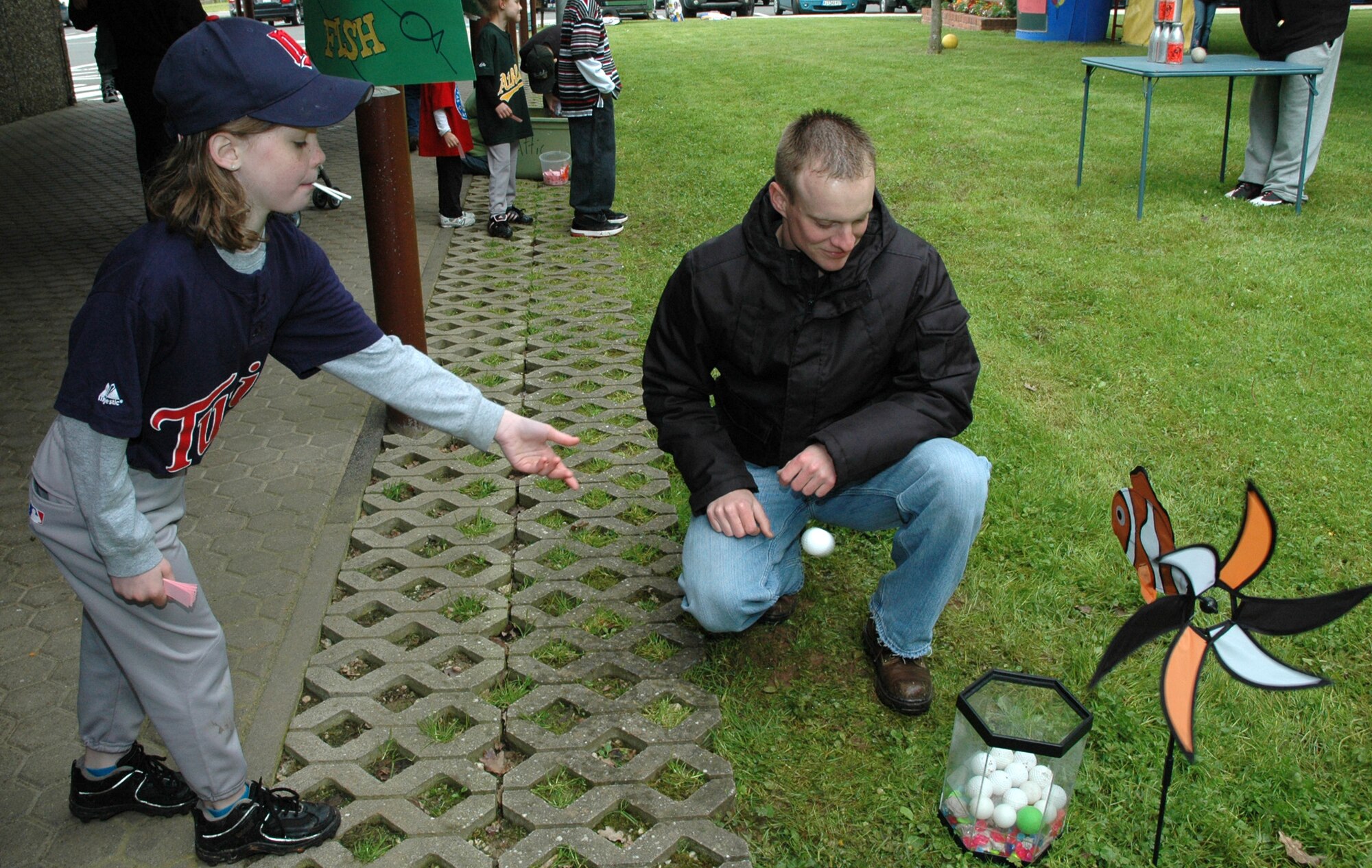 SPANGDAHLEM AIR BASE, Germany -- Volunteer Airman 1st Class Mathew Vincie looks on as Natalie Jackson tries to land a ping pong ball in the fish tank to catch a prize May 16, 2009 at the Spangdahlem Elementary School Parent-Teacher-Student Association Spring Carnival. Airman Vincie is assigned to the 52nd Civil Engineer Squadron. (Photo by Bobbie Gonzales)
