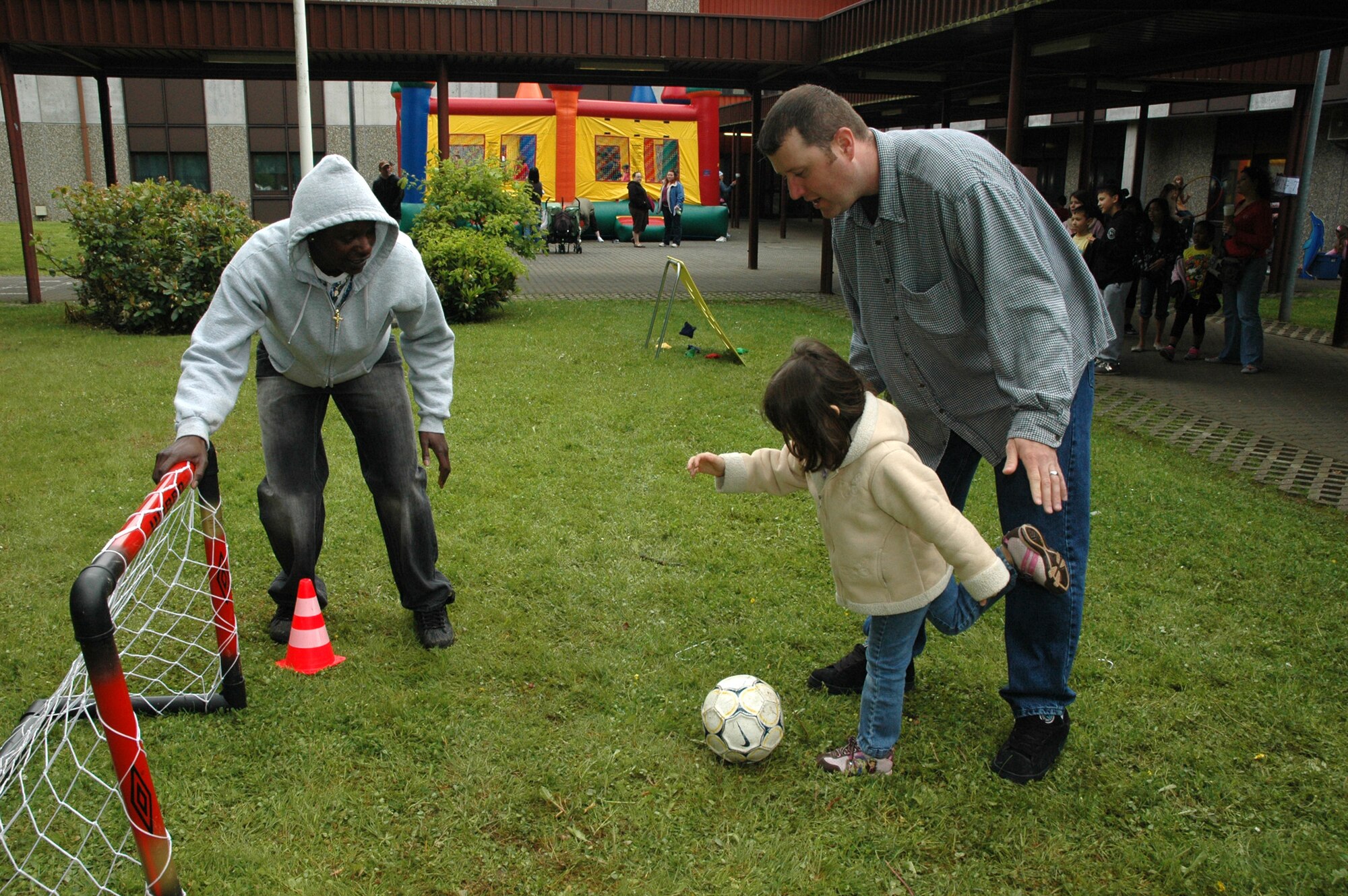 SPANGDAHLEM AIR BASE, Germany -- “Goal!”  Senior Airman Tommiah Walker and Tech. Sgt. Eric Brown help Annelise Brown practice her soccer skills May 16, 2009 at the Spangdahlem Elementary School Parent-Teacher-Student Association Spring Carnival. Airman Walker, 52nd Civil Engineer Squadron, and Sergeant Brown, 52nd Security Forces Squadron, both volunteered their time to help make the carnival a success. (Photo by Bobbie Gonzales)