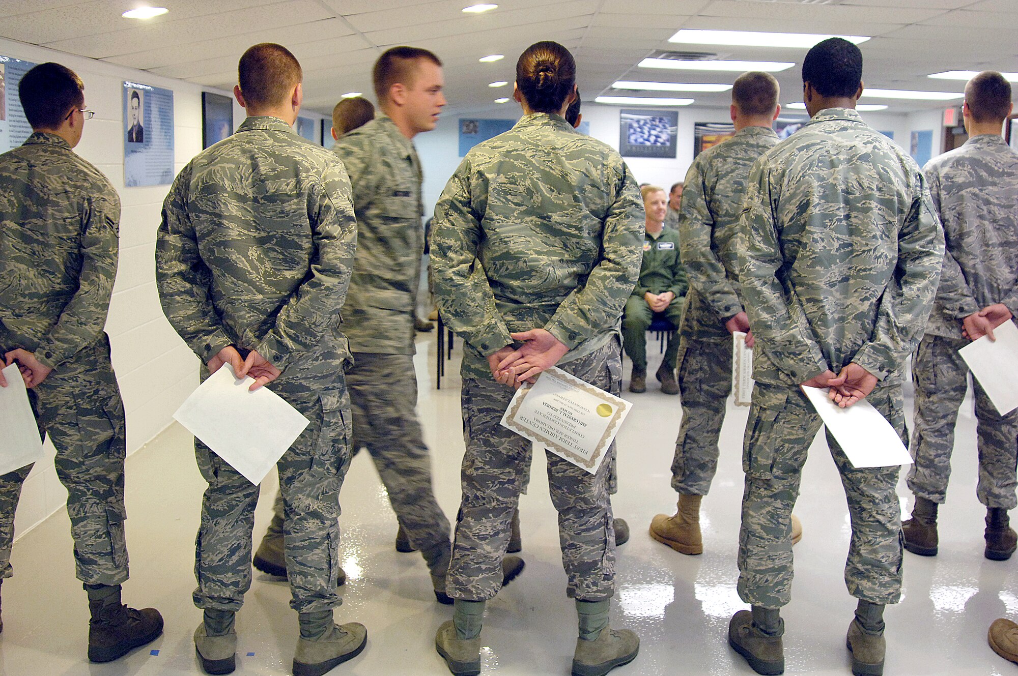 FTAC members hold their graduation certifications as another Airman makes his way to the front in a May 15 ceremony.  An audience of senior enlisted and officers attend, afterward to welcome the Airmen into their squadrons. This class was mostly 552nd Air Control Wing Airmen. (Air Force photo/Margo Wright)