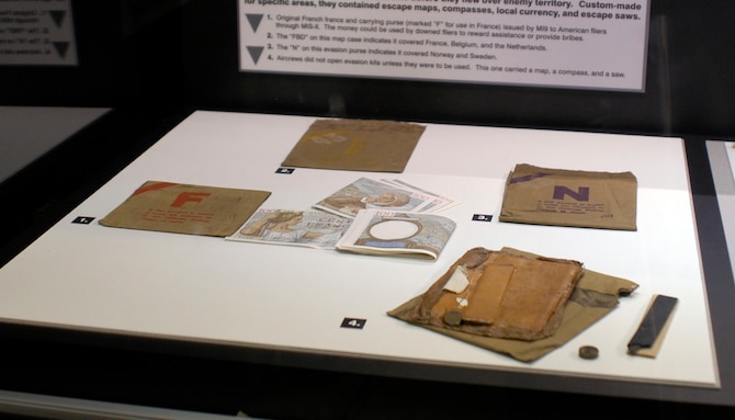 DAYTON, Ohio - Evasion purses: 1) original French francs and carrying purse (marked "F" for use in France) issued by M.I.9 to American flyers through MIS-X. The money could be used by downed flyers to reward assistance or provide bribes. 2)The “FBD” on this map case indicates it covered France, Belgium, and the Netherlands. 3) The “N” on this evasion purse indicates it covered Norway and Sweden. 4) Aircrews did not open evasion kits unless they were to be used.  This one carried a map, a compass and a saw. (U.S. Air Force photo)
