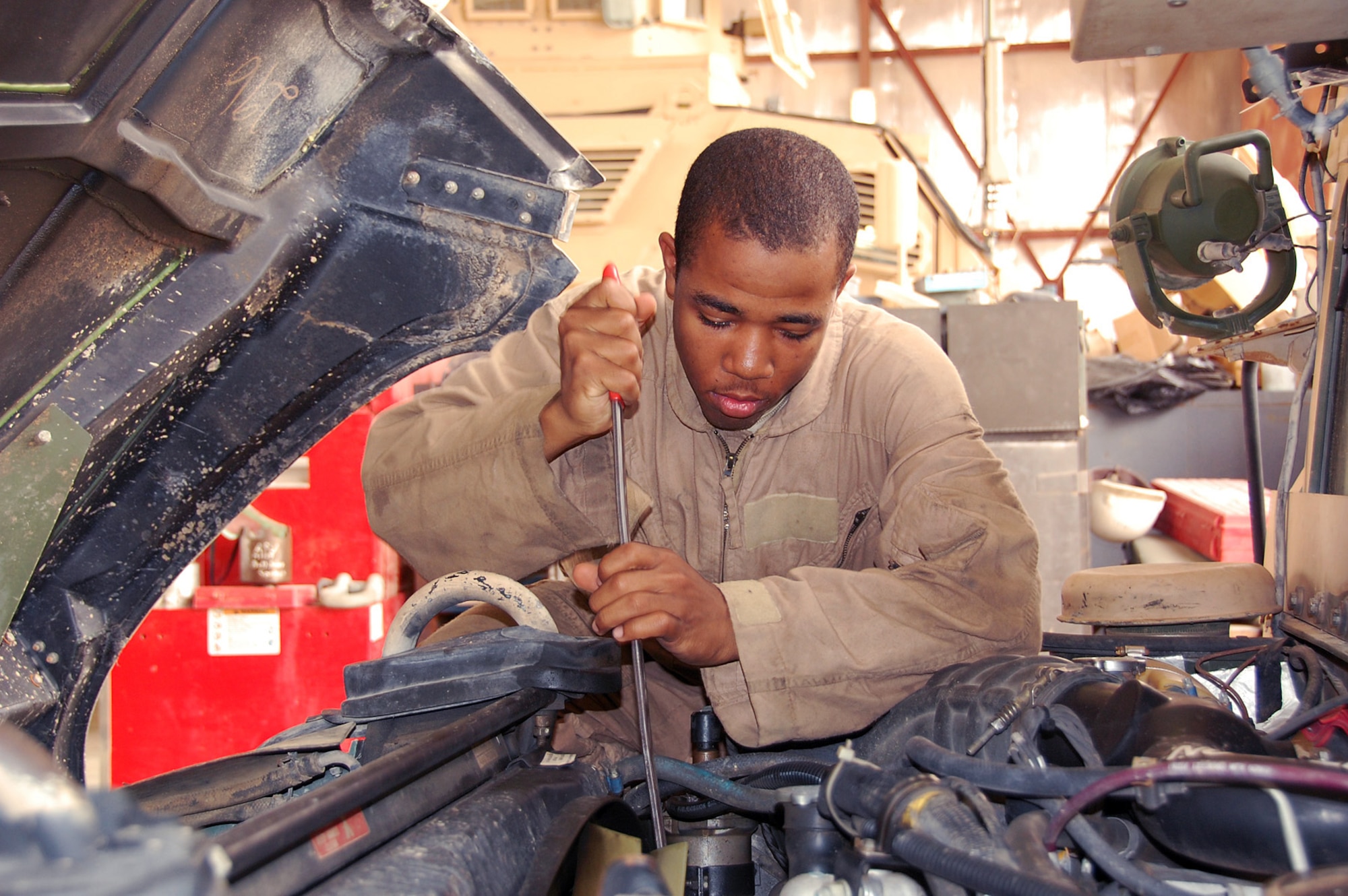 Senior Airman Marcel Edwards works on a Humvee engine May 11 at the Camp Bucca motor pool in Iraq. Four Airmen from the 887th Expeditionary Security Forces Squadron work alongside Army vehicle maintainers to keep the squadron's Humvees, mine-resistant ambush-protected vehicles and other camp vehicles working. Airman Edwards is an 887th ESFS vehicle technician. (U.S. Air Force photo/Staff Sgt. Thomas J. Doscher) 
