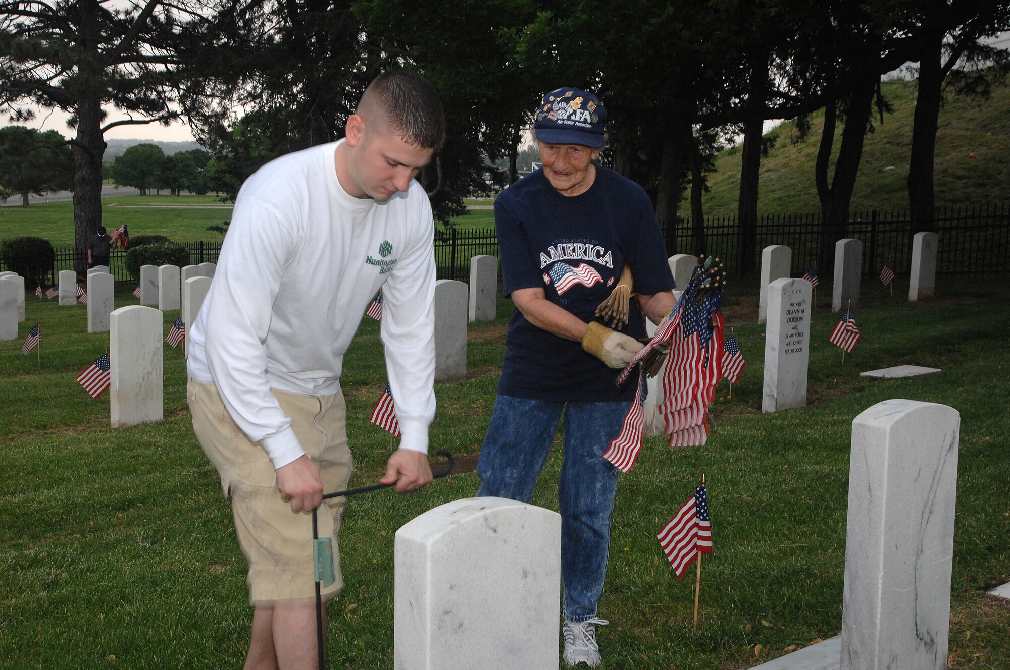 OFFUTT AIR FORCE BASE, Neb. -- Senior Airman Matthew T. Petway, 55th Comptroller Squadron and Cathy McCoy, wife of retired Chief Master Sgt. of the Air Force James M. McCoy, place American flags in front of headstones inside the Offutt Cemetery May 25. Placing the flags was part of preparation for Offutt's Memorial Day ceremony. U.S. Air Force photo by Leticia Cunningham