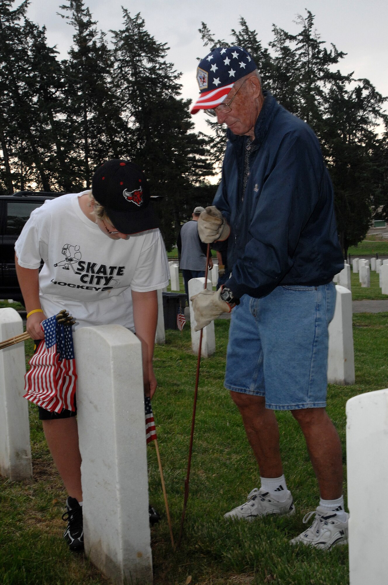 OFFUTT AIR FORCE BASE, Neb. - Retired Chief Master Sgt. of the Air Force James M. McCoy and his grandson David, place American flags in front of headstones inside the Offutt Cemetery May 25. The flag placement was part of preparation for Offutt's Memorial Day ceremony. U.S. Air Force photo by Leticia Cunningham

