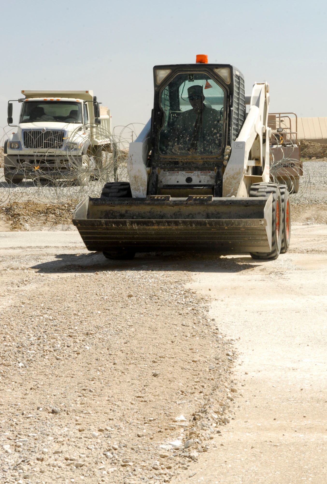 BAGRAM AIR FIELD, Afghanistan- Airman 1st Class Sheldon Mellott, 455th Expeditionary Civil Engineer Squadron, drives a Bobcat to flatten dirt for a foundation to extend an A-10 aircraft hangar May 27. The hangar extension will be used to support alert crews on standby. The project costed roughly $156,000 for rock and concrete materials. Airman Mellott hails from Salt Lake City, Utah and is deployed from the 509th Civil Engineer Squadron at Whiteman Air Force Base, Mo. (U.S. Air Force photo/Senior Airman Erik Cardenas)