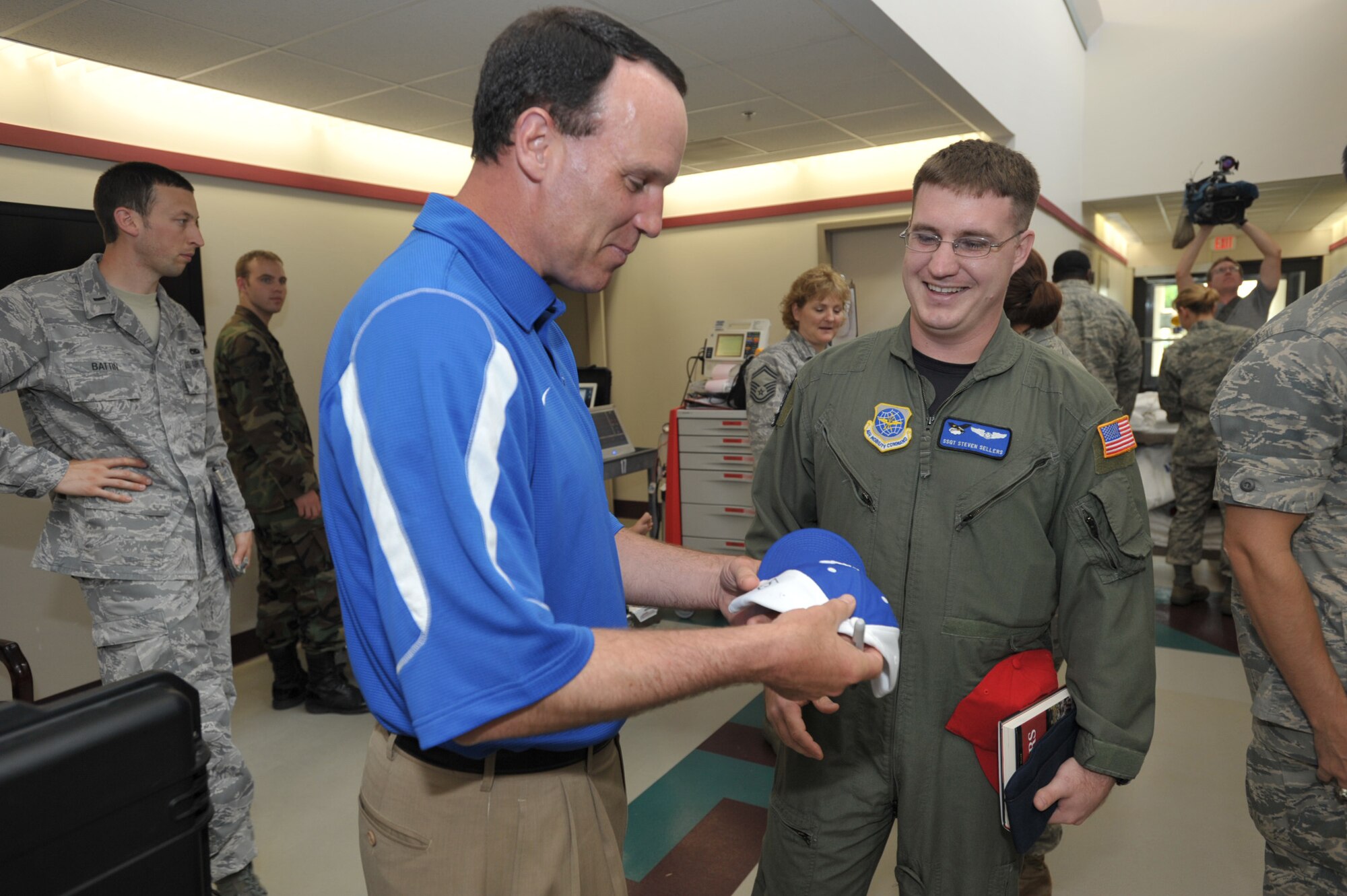 Troy Calhoun, head coach of the Air Force football team, gives an autographed hat to Staff Sgt. Steve Sellers during a visit to McConnell Air Force Base, Kan., on May 27. Coach Calhoun and two other NCAA football coaches--Jim Grobe of Wake Forest and Jim Tressel of Ohio State--were at the base to kickoff Coaches Tour 2009, a second annual morale-boosting mission that brings icons of college football to U.S. servicemembers. Sergeant Sellers is a KC-135 Stratotanker boom operator and native of Killeen, Texas. (U.S. Air Force photo/Tech. Sgt. Jason Schaap)