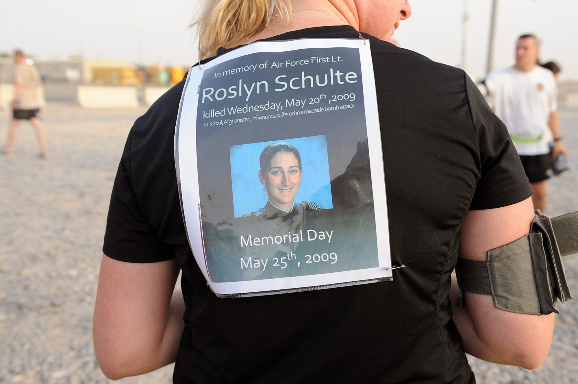 SOUTHWEST ASIA -- Navy Petty Officer 1st Class Kelli Roesch of Portland, Ore., wears a sign in honor of fallen servicemember Air Force 1st. Lt. Roslyn Schulte during a Memorial Day 5K run May 25. Lieutenant Schulte died May 20th in Afghanistan from a roadside bomb. Petty Officer Roesch trained with Lieutenant Schulte at Ft. Lewis, Wash., prior to their transfer to separate locations in the Middle East. "First Lt. Schulte was a great officer and even better person whose loss is rippling across many friends and fellow servicemembers who knew and admired her," said Petty Officer Roesch.   (U.S. Navy photo by Navy Petty Officer 2nd Class Jorge Saucedo)