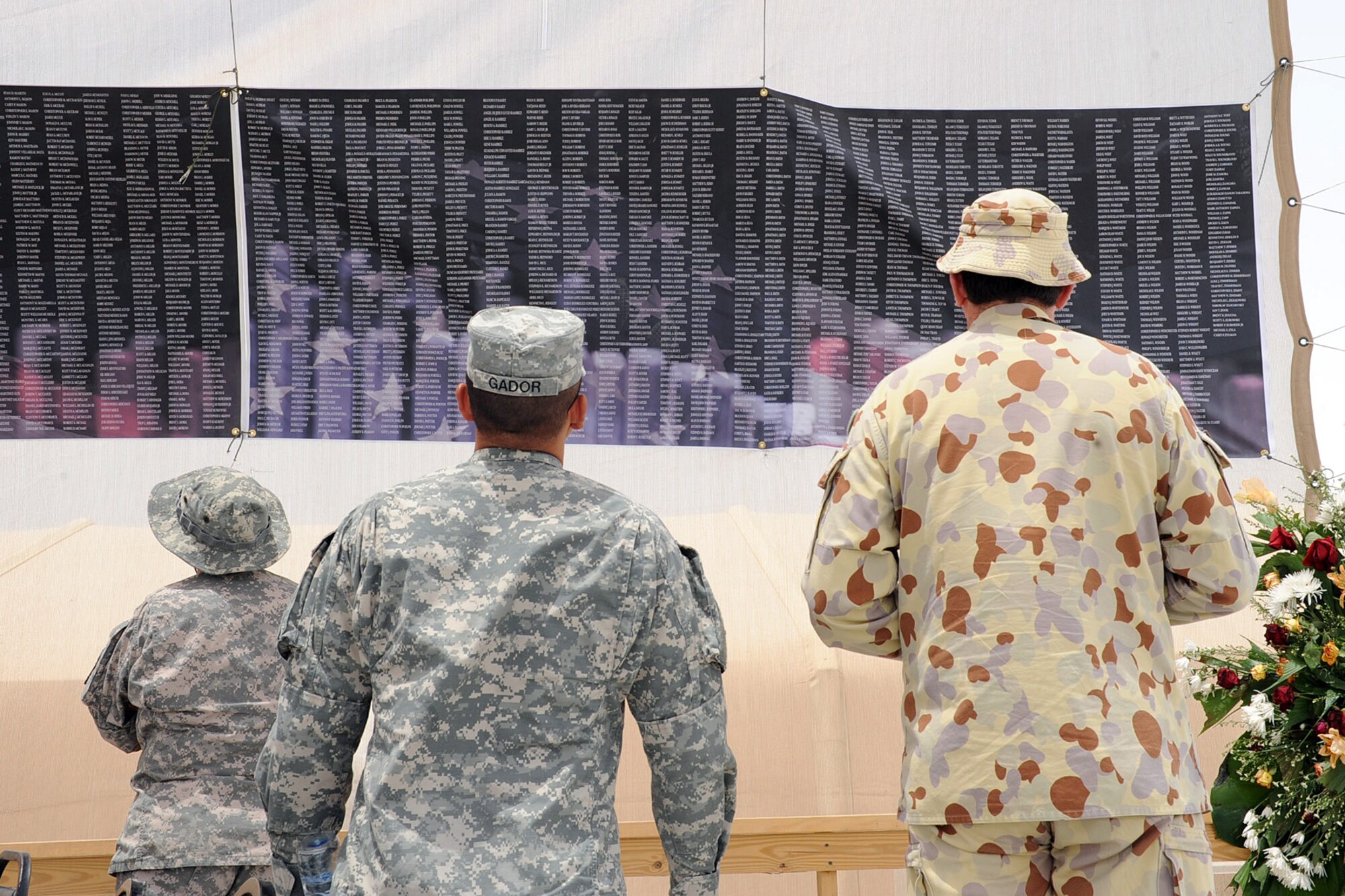 SOUTHWEST ASIA -- Army and Australian Forces members look at a banner listing the names of all the service members who died in support of Operations Iraqi Freedom and Enduring Freedom last year and up to May after the Memorial Day Service on a base in the Middle East May 25. (U.S. Navy photo by Navy Petty Officer Second Class Jorge Saucedo)