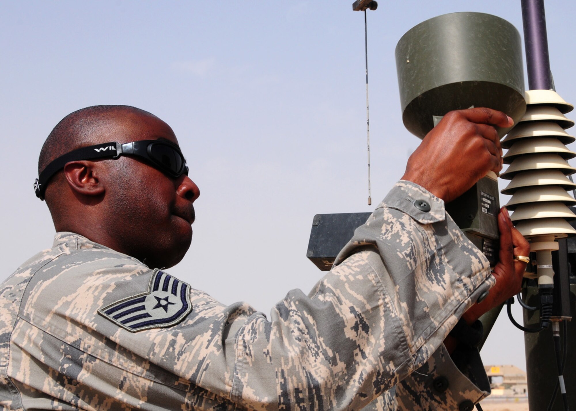SOUTHWEST ASIA -- Staff Sgt. Christopher Walton, 386th Expeditionary Operations Support Squadron, removes the rain gauge from the Tactical Meteorological Observing System-53 during a weekly cleaning at an air base in Southwest Asia, May 26. Due to the environmental conditions including sand, wind, and dust, the TMQ-53 must be inspected and cleaned weekly to ensure accurate rain fall totals. Sergeant Walton is currently deployed from Ramstein Air Base, Germany, and is originally from Atlanta. (U.S. Air Force photo/ Senior Airman Courtney Richardson)