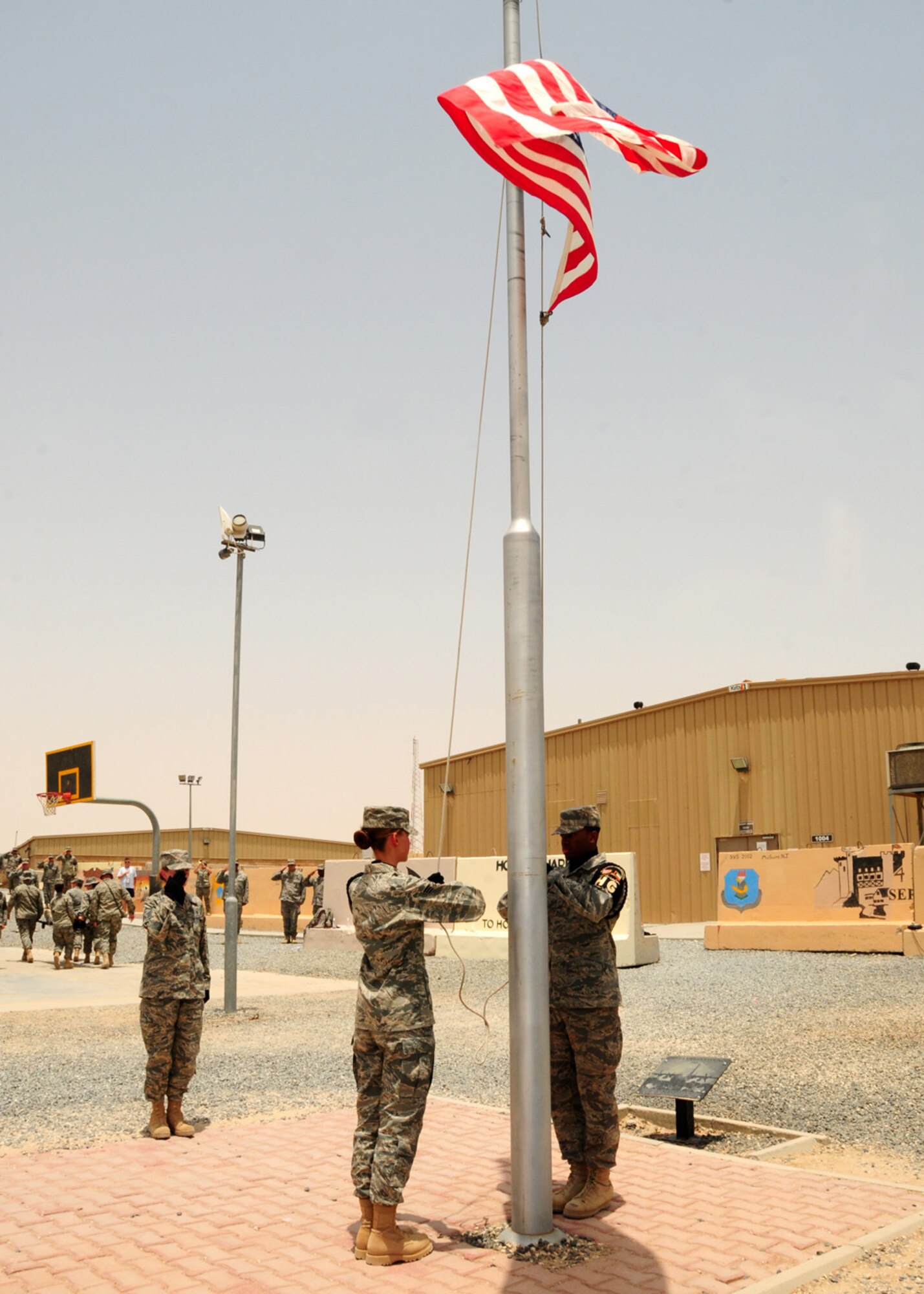 SOUTHWEST ASIA -- Honor Guard members Senior Airman Amanda Rosner, 386th Expeditionary Maintenance Squadron, and Airman 1st Class Ronell Wilder, 386 Expeditionary Logistics Readiness Squadron, raise the American flag during the Memorial Ceremony as Master Sgt. Betsi Keltz, 43rd Expeditionary Electronic Combat Squadron, salutes in respect and honor for those who have died in our nation's service at an air base in Southwest Asia, May 25. Memorial Day was officially proclaimed May 5, 1868, by General John Logan, national commander of the Grand Army of the Republic and was first observed May 30, 1868. Airman Rosner is deployed from Yokota Air Base, Japan, and is originally from Alvin, Wis. Airman Wilder is deployed from Hurlbert Field Air Force Base, Fla., and is originally from Belzoni, Miss. Sergeant Keltz is deployed from Davis-Monthan Air Force Base, Ariz., and is originally from Kingston, N.Y. (U.S. Air Force photo/ Senior Airman Courtney Richardson)