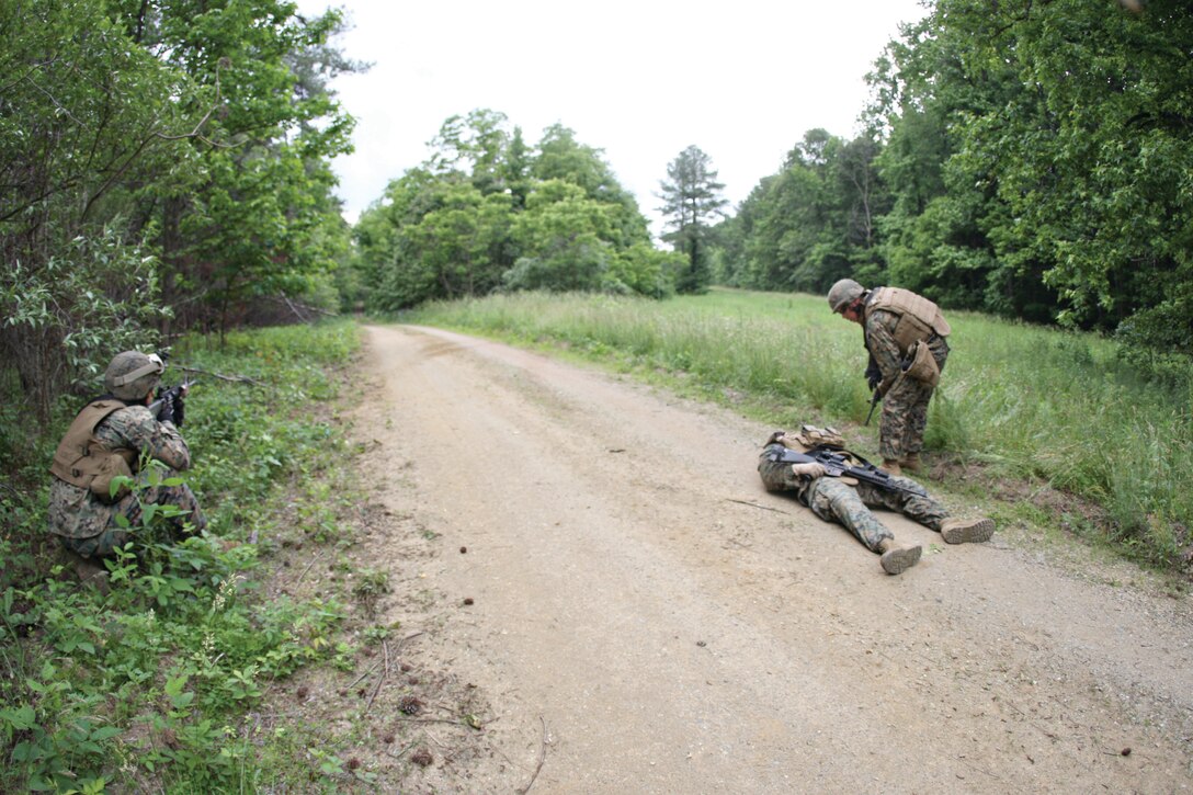 A Marine with Headquarters and Service Company, 3rd Battalion, 6th Marine Regiment, 2nd Marine Division, provides security at a compromised entry control point as another Marine assesses the wounds of a casualty during a casualty evacuation drill during Exercise A.P. Hill.