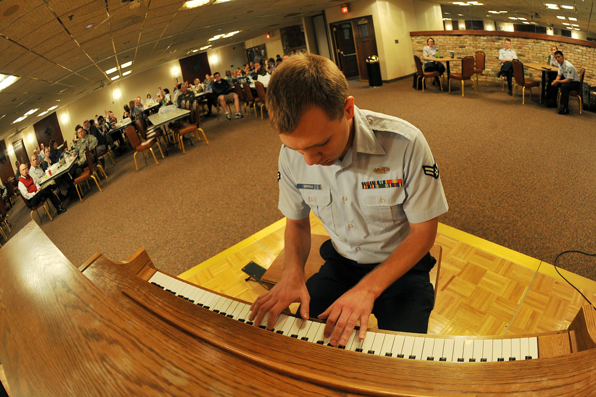 OFFUTT AIR FORCE BASE, Neb., -- Airman 1st Class Michael Srstka, a pianist with the Heartland of America Band, plays the piano as members of Team Offutt look on during the first concert of the Lunch Bachs concert series at the Community Center here  May 28. The concert series consists of four 45-minute performances. U.S. Air Force photo by Charles Haymond
