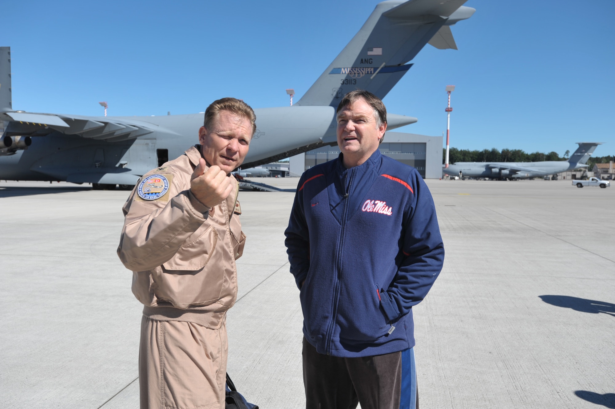 Houston Nutt, head football coach at Ole Miss, talks with Col. Bart Weiss just after they arrived at Ramstein Air Base, Germany, on May 29. The stop was part of Coaches Tour 2009, a morale-boosting mission that brings NCAA football coaches to U.S. servicemembers. Behind Coach Nutt is a C-17 assigned to an Air National Guard unit in his home state of Mississippi. Colonel Weiss will soon takeover as vice commander of McConnell Air Force Basel, Kan., and is former star quarterback for the Air Force football team. (U.S. Air Force photo/Tech. Sgt. Jason Schaap)