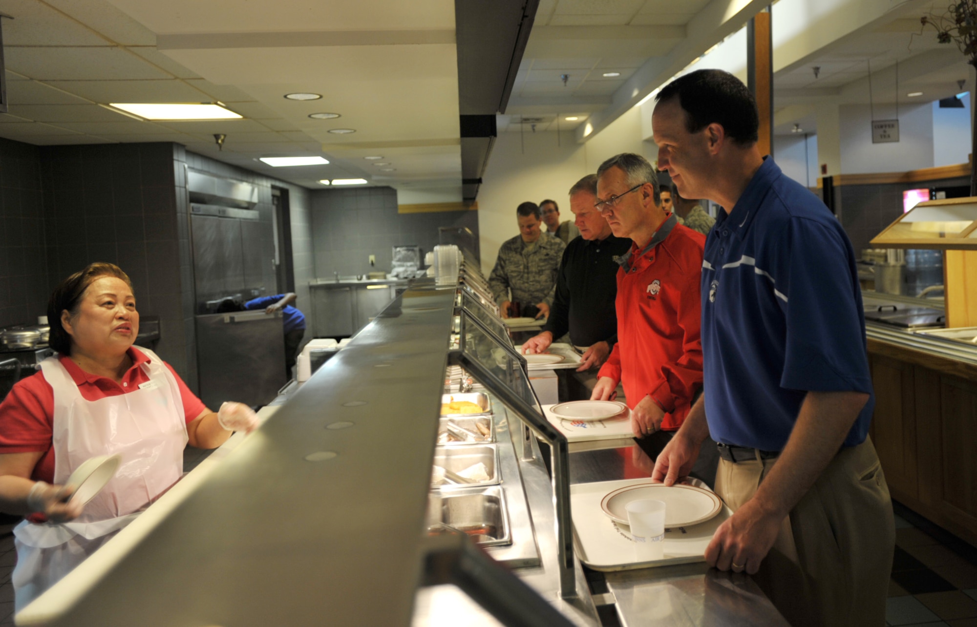 Three NCAA head football coaches--Troy Calhoun of Air Force (in blue), Jim Tressel of Ohio State (in red), and Jim Grobe of Wake Forest (in black)--started May 28 at McConnell Air Force Base, Kan., telling Teresita "Shorty" Walline what they would like for breakfast. McConnell was the first stop of Coaches Tour 2009, a morale-boosting mission that brings NCAA coaches to U.S. servicemembers.
Walline is a mess attendant at the base dining facility, where the coaches soon after attended a breakfast with regular, reserve and national guard Airmen. The Coaches Tour is organized by Morale Entertainment, LLC., in association with Armed Forces Entertainment. (U.S. Air Force photo/Tech. Sgt. Jason Schaap)