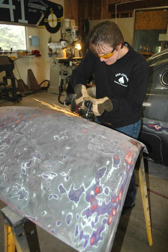 Tech. Sgt. Angie Wright, 512th Maintenance Squadron, removes paint from the hood of a 1950's Ford Mercury in her and her husband's family-owned metals shop. Her husband is Senior Airman Michael Wright who works in the 512th Maintenance Squadron Aircraft Metals Technology Shop. The two of them are restoring the vehicle, which should be on display at the Delaware Street Rod Show in Harrington, Del., June 30. (U.S. Air Force/Capt. Marnee A.C. Losurdo)