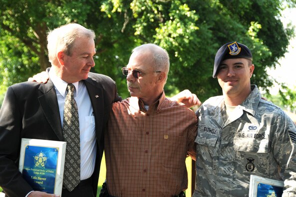 Special Agent Ross Bergstresser (left), Air Force Office of Special Investigations, and Staff Sgt. Matt Treadwell (right), 97th Security Forces Squadron, hug Deputy Kevin Walker at a ceremony May 22 in Altus, Okla. Deputy Walker had a heart attack May 14 at the firing range during a competition between Altus Police Department, Altus AFB Security Forces and OSI. These two heroes saved Deputy Walker's life, and kept him alive until emergency medical attention arrived earning the Fraternal Order of Police Life Saver Award. (U.S. Air Force photo/Senior Airman Marianne E. Lane)