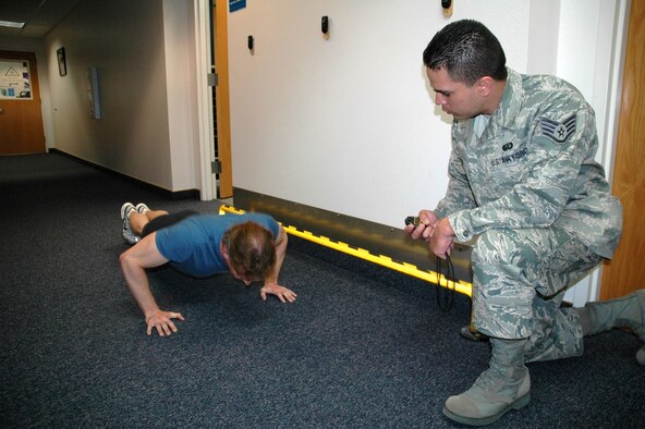 Staff Sgt. Kwinton Estacio, 341st Force Support Squadron fitness specialist, times Eric Thayer, 341st FSS community readiness consultant, as he completes push-ups during an Air Force physical fitness test May19 at the base health and wellness center. Mr. Thayer scored 100 points, making this test his fifth consecutive perfect score in as many years. (U.S. Air Force photo/Senior Airman Dillon White)