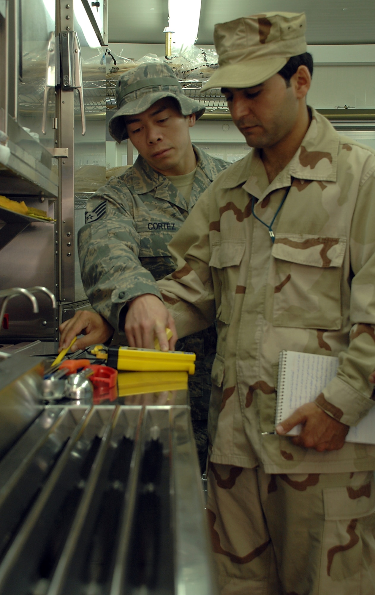 KIRKUK REGIONAL AIR BASE, Iraq –Staff Sgt. Venerando Cortez, 506th Expeditionary Medical Squadron, deployed from Eglin Air Force Base, Fla., shows Iraqi Air Force medical technician, Warrant Officer Ghassan, how to check the temperature of hot food items during food service training here May 3. The Angeles City, Philippines, native trained Iraqi Airmen in kitchens of AAFES food service facilities here so they can learn how to conduct food inspections. (U.S. Air Force photo / Senior Airman Jessica Lockoski)