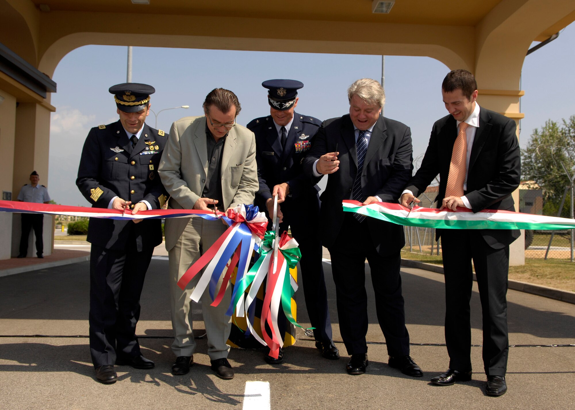 Col. Filippo Zampella, left, the Italian Air Force "Pagliano e Gori" Airport commander, Brig. Gen. Craig Franklin, center, 31st Fighter Wing commander, and three Italian representatives from the Friuli Venezia Giulia Region, Province of Pordenone and the City of Roveredo, cut the ribbon for the new South Gate entrance at Aviano Air Base, Italy, during a ceremony May 26, 2009. The gate is the new 24-hour gate and is located near the Area F softball fields and outdoor recreation. (U.S. Air Force photo/ Staff Sgt. Mercedes Crossland)