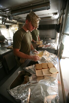 Lance Cpl. Alexander Angelikas, a food service specialist with Combat Logistics Battalion 4, 2nd Marine Logistics Group (Forward), prepares a sandwich for a Marine with Company A, 1st Battalion, 7th Marine Regiment, at Contingency Outpost Viking, Iraq, May 30, 2009. The six Marines from CLB-4 are able to cook one to three hot meals a day for the Marines and sailors aboard COP Viking. (U.S. Marine Corps photograph by Cpl. Robert S. Morgan)