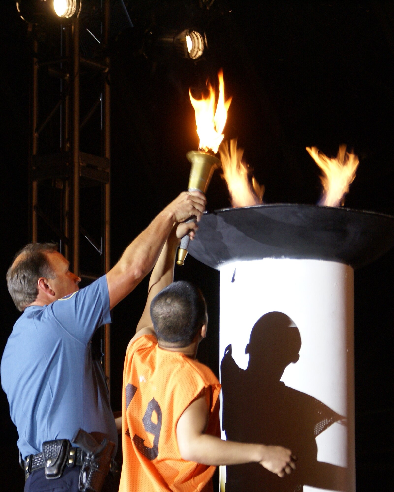 Athlete Brandon Geverola of the Fort Lewis Tigers, and Lt. Mike Merriman, Yakima Police Department, light the flame that signals the opening of the annual Special Olympics Washington Summer Games here May 29. McChord and Fort Lewis are teamed up to host more than 8,000 athletes, coaches and volunteers participating in the annual Summer Games. Events including aquatics, athletics (field events), cycling, power lifting, and soccer are part of this year's competition. (U.S. Air Force photo/Staff Sgt. Eric Burks)