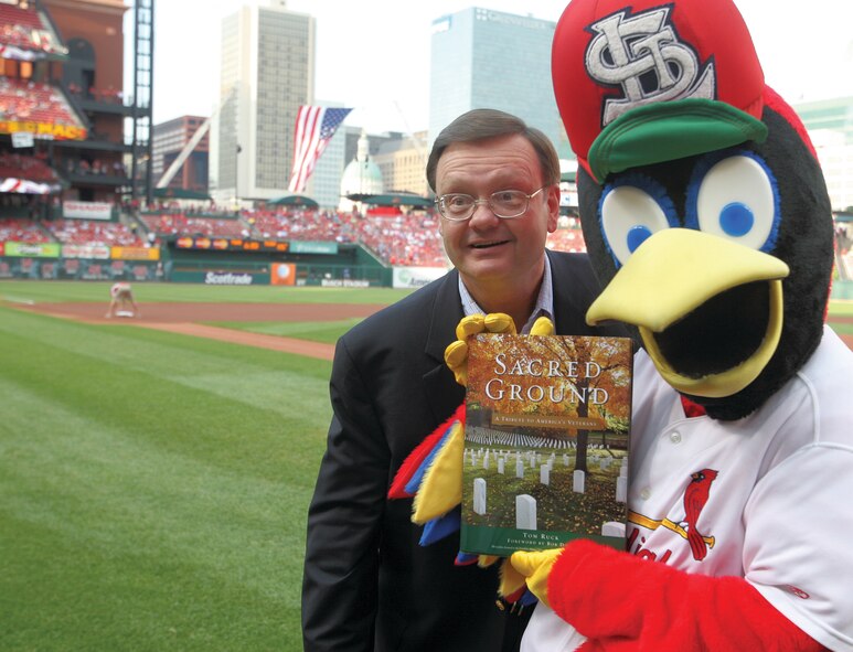 Fredbird, the mascot for the St. Louis Cardinals baseball team, holds a copy of  “Sacred Ground.” The team invited Tom Ruck (left) to throw the first pitch of their game May 22. (photo courtesy of Tom Ruck)