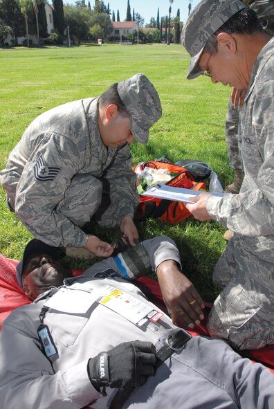 163d Medical Group member Tech. Sgt. John Reed puts a tourniquet on a patient with a simulated severed arm while 163 MDG Commander Col. Vincent Dang prescribes further treatment in the makeshift triage treatment center that was set up to care for injured people during an earthquake exercise called the Great California ShakeOut. (U.S. Air Force photo by Senior Airman Paul Duquette)