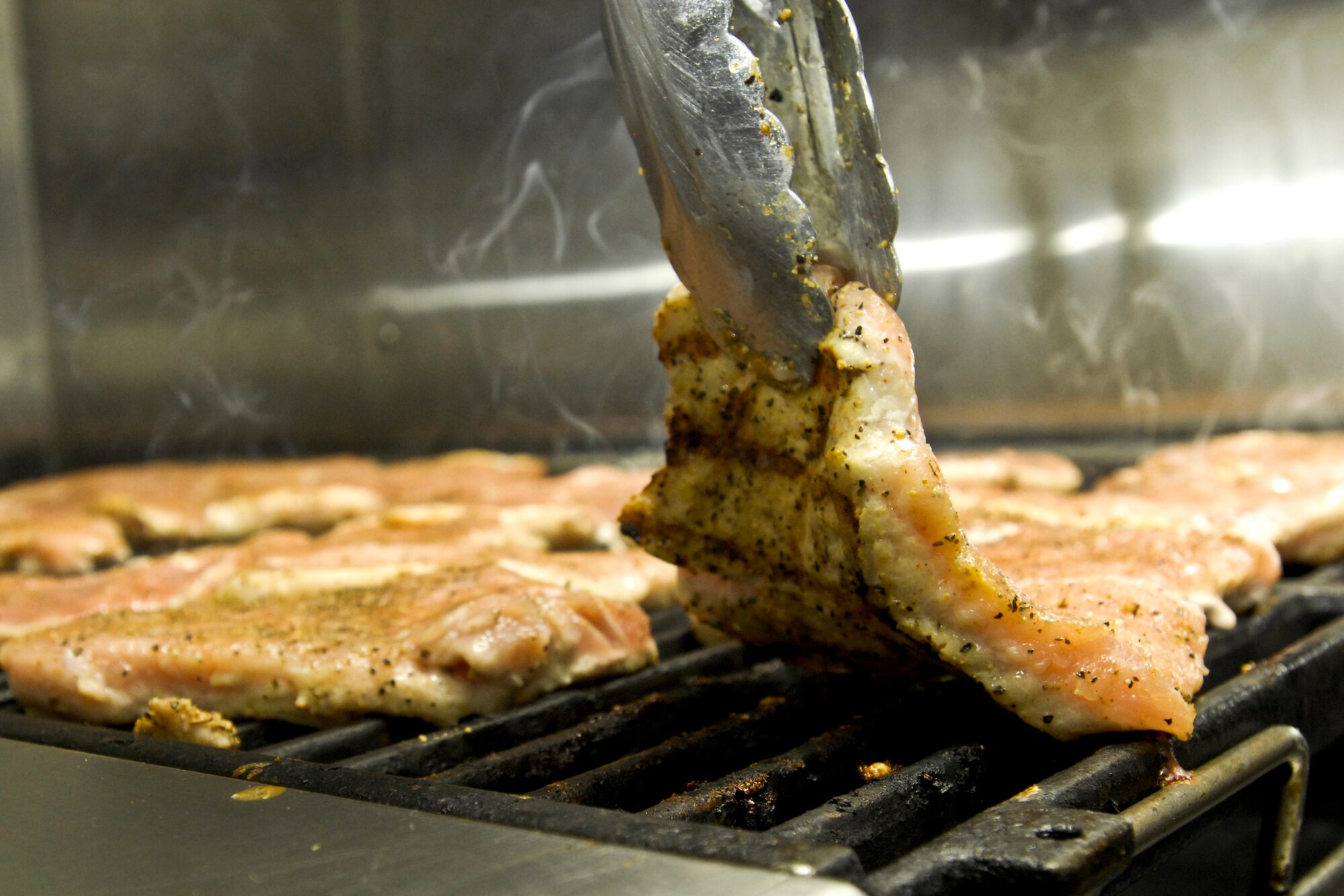 ELMENDORF AIR FORCE BASE, Alaska – Senior Airman Angel Ramirez, 3rd Force Support Squadron food service apprentice, checks one side of a pork chop to see if it’s done Oct. 29 at the Iditarod Dining Hall. Ramirez was selected as one of the 2009 John L. Hennessy award winners earlier this year, which recognizes culinary excellence. (U.S. Air Force photo/Airman 1st Class Christopher Gross)