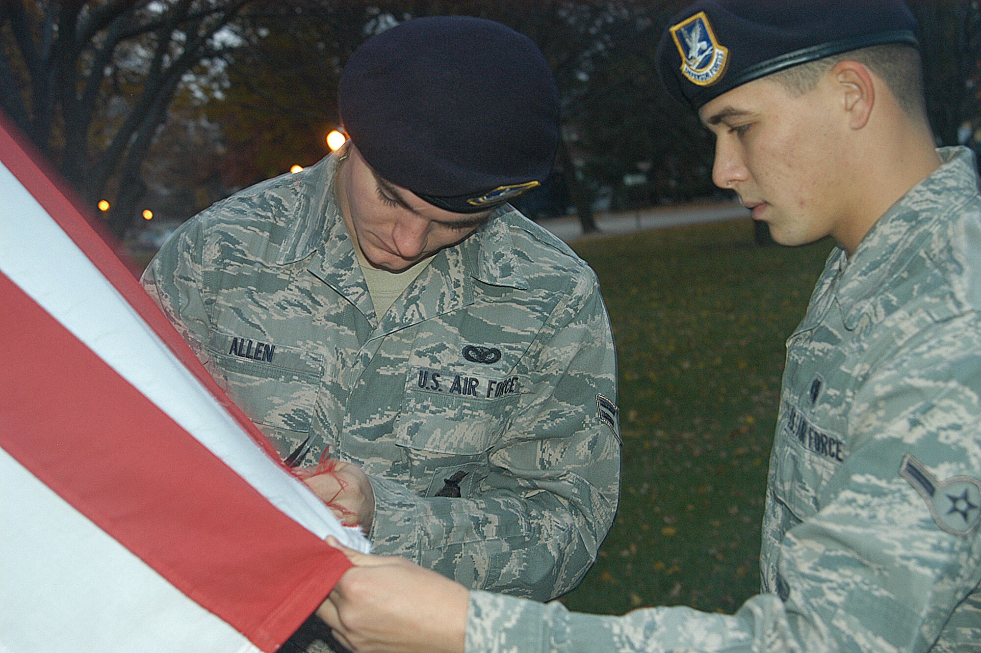OFFUTT AIR FORCE BASE, Neb. - Airman 1st Class Jonathan P. Allen, 55th Security Forces Squadron, carefully removes strings from an American flag at the parade grounds here as Airman Jared T. Schnell, holds the flag steady Oct. 28. The Airmen were part of a morning detail responsible for removing strings from all 26 flags that fly at the Offutt parade grounds. Both Airmen said it's important to ensure the American flag is well taken care of as its represents freedom and the sacrifices of all servicemembers past and present. U.S. Air Force Photo by Staff Sgt. James M. Hodgman