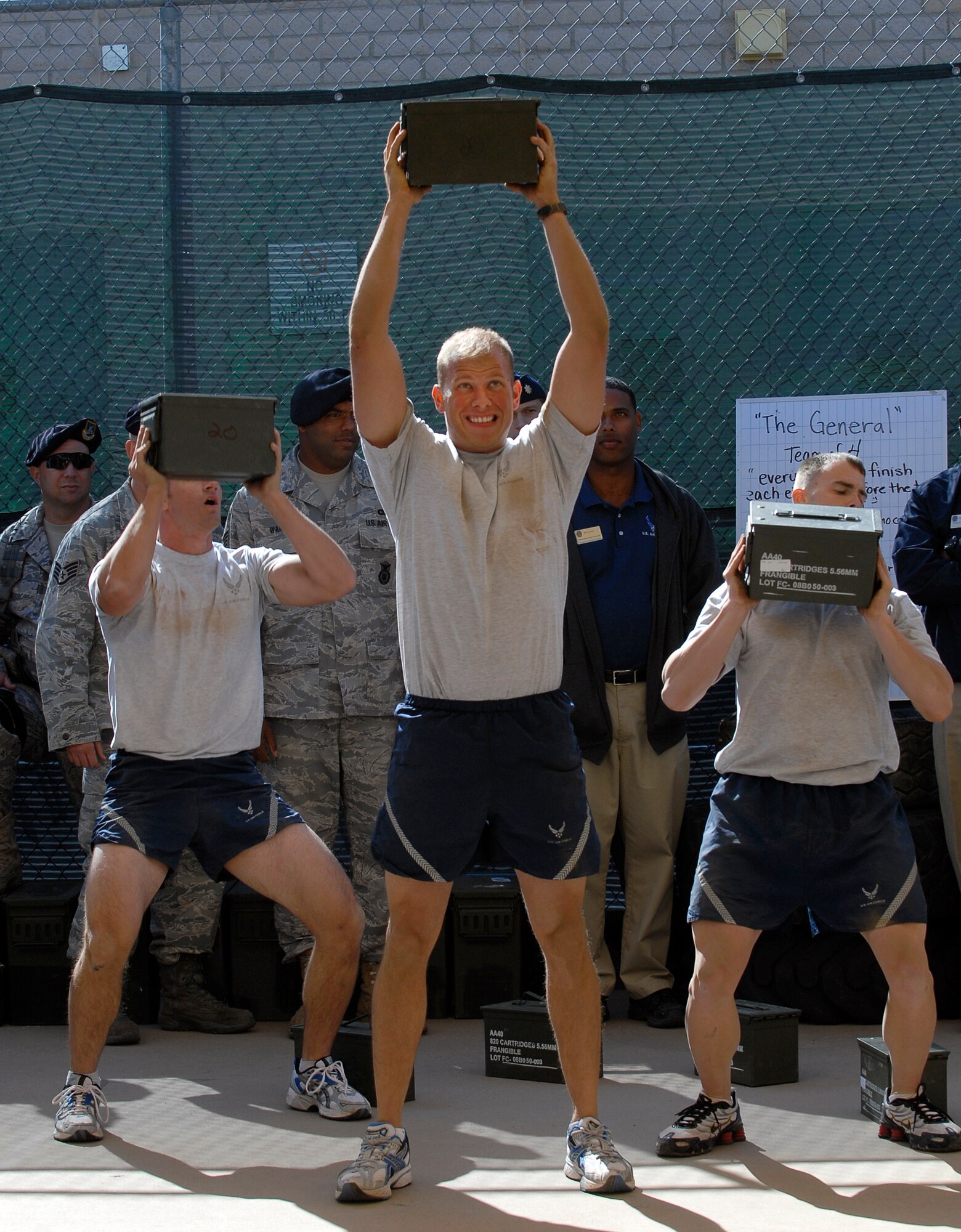 Members of the 56th Security Forces Squadron perform overhead presses with weighted ammo-cans during a demonstration run through the new Combat PT Course on Luke Air Force Base, Ariz.  (U.S. Air Force photo by Tech. Sgt. Jeffrey A. Wolfe)
