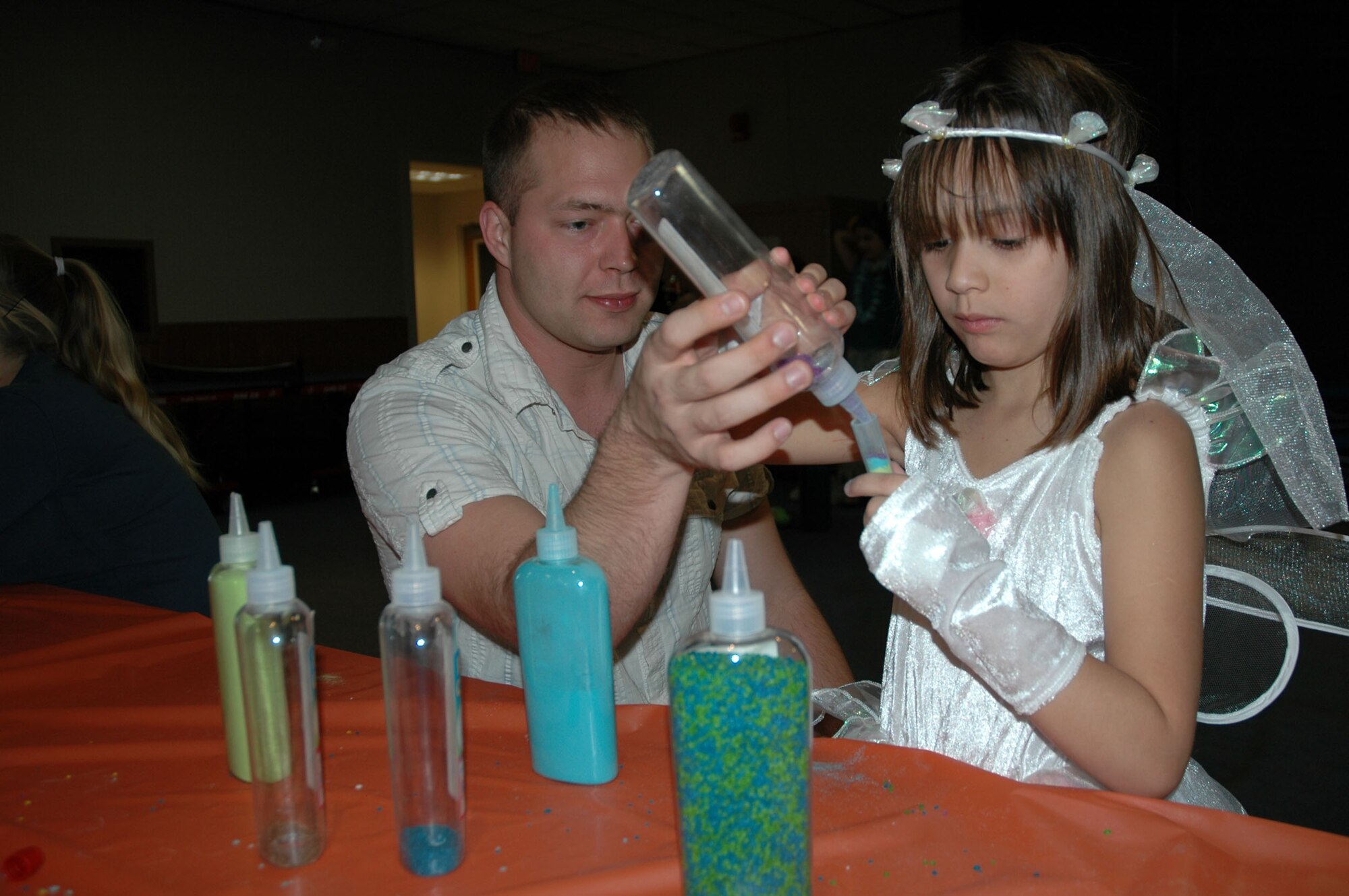 Staff Sgt. Jamie Neely, 341st Maintenance Operations Squadron, helps his daughter Carisa, 7,  make a candy stuffed tube at the Youth Center's Fall Festival Oct. 30. (U.S. Air Force photo/Senior Airman Dillon White)