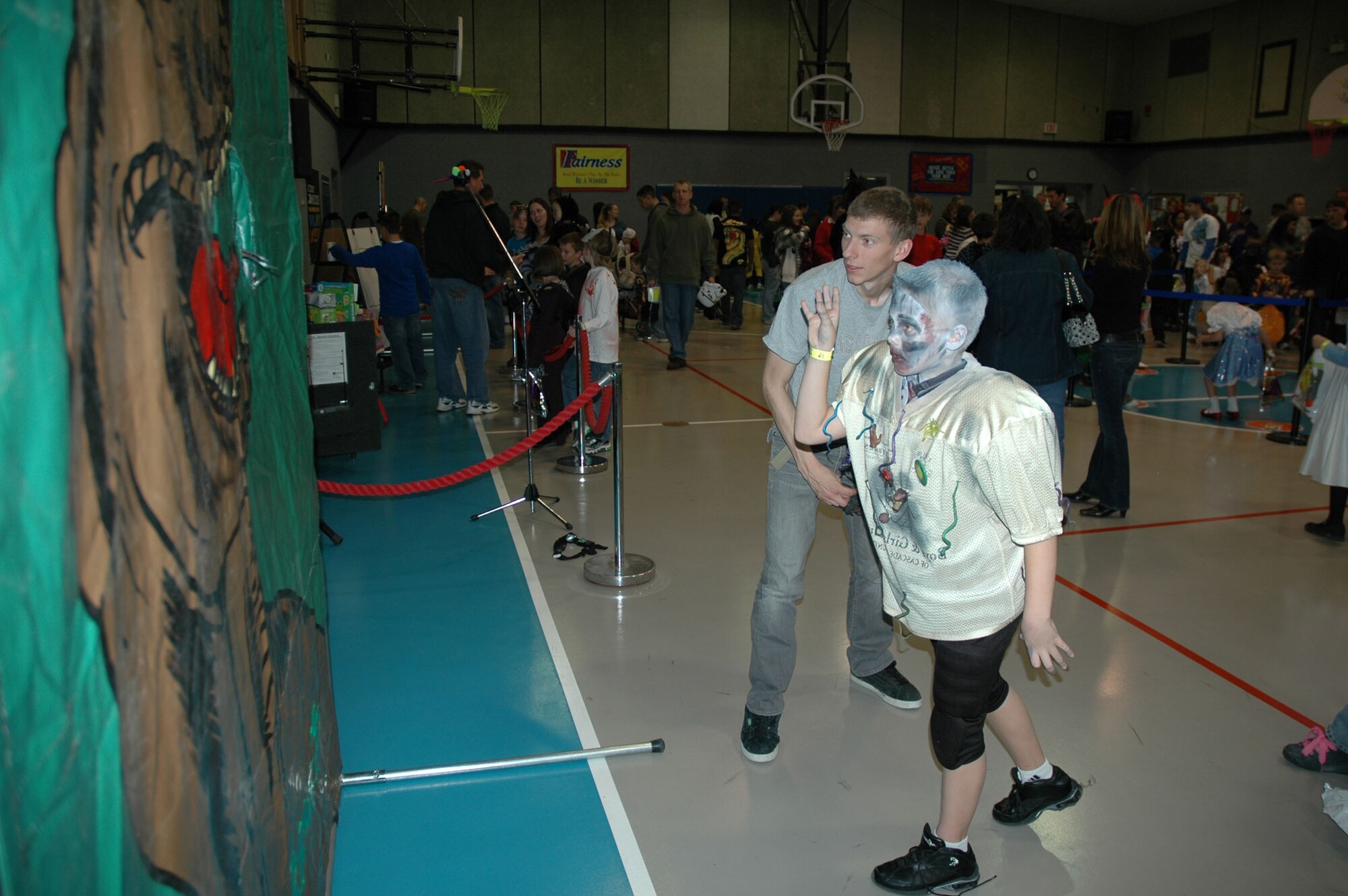 Airman 1st Class Thomas Stavlo, 341st Security Forces Group Tactical Response Force member, watches as 10-year-old Jared, tosses an object through the hole at the Youth Center's Fall Festival Oct. 30. (U.S. Air Force photo/Senior Airman Dillon White)